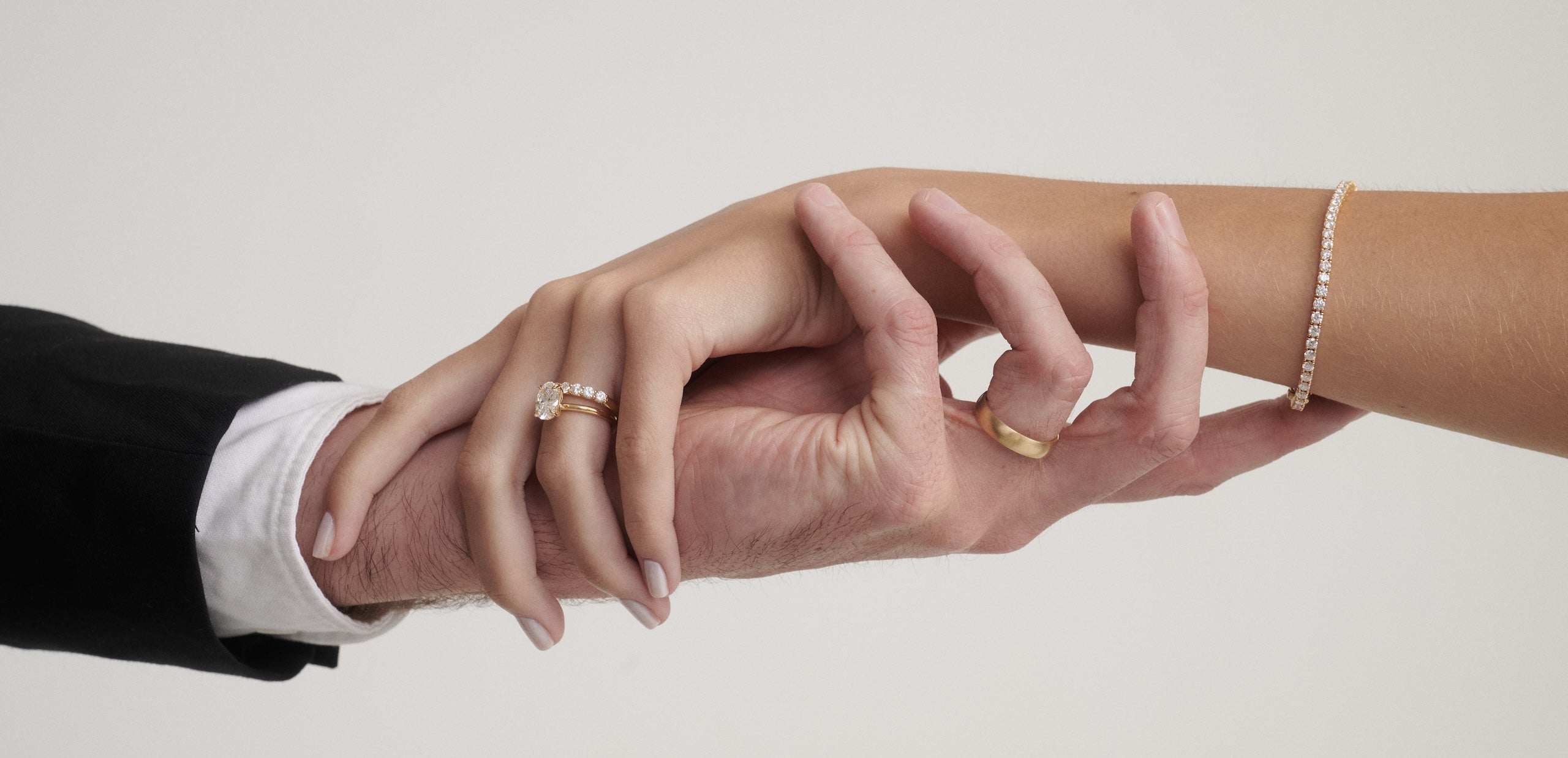 Man and woman's hands with wedding rings on each hand and diamond tennis bracelet on woman's hand