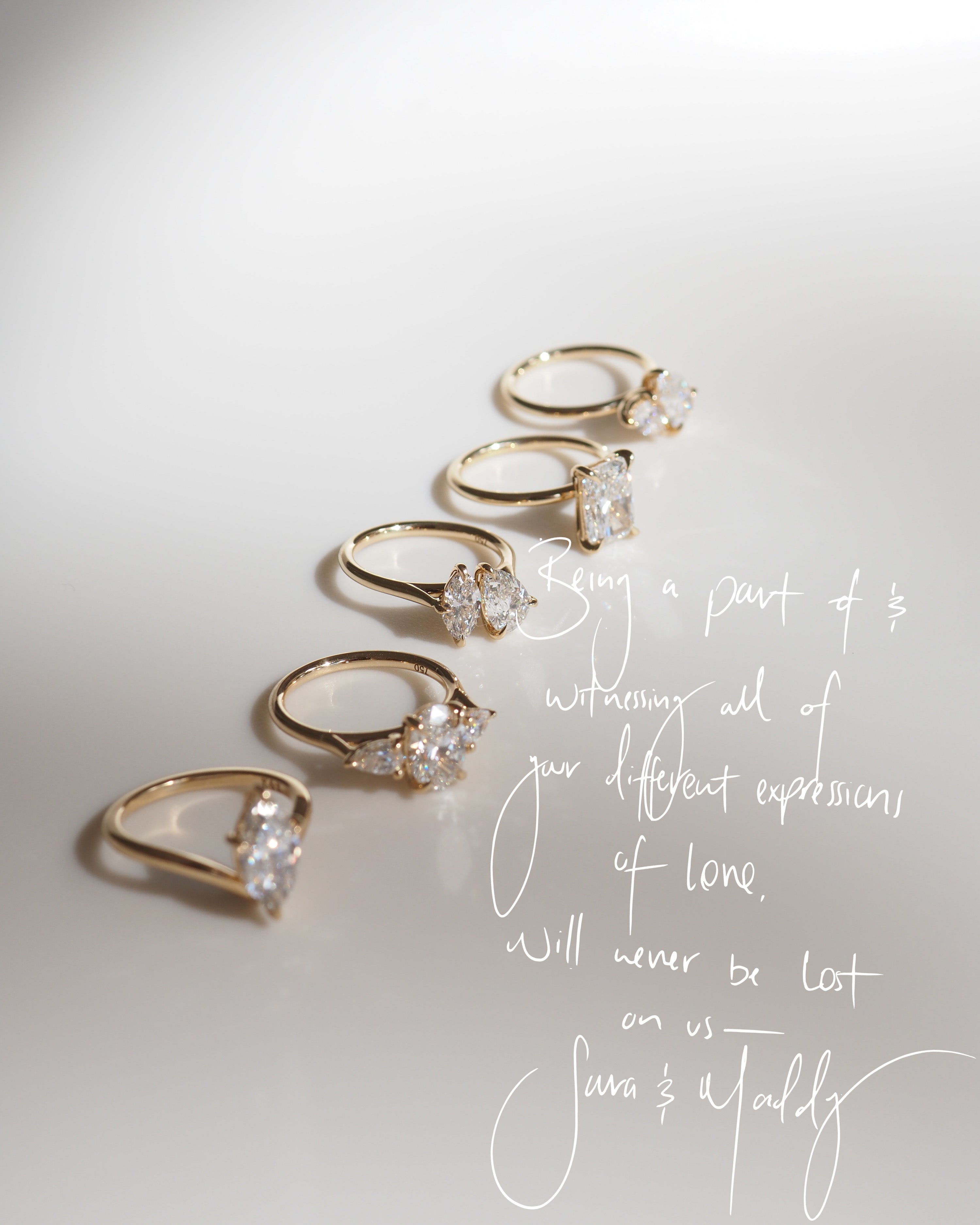 Five elegant gold rings with various diamond settings arranged in a diagonal line on a white surface. Handwritten text overlays the image.