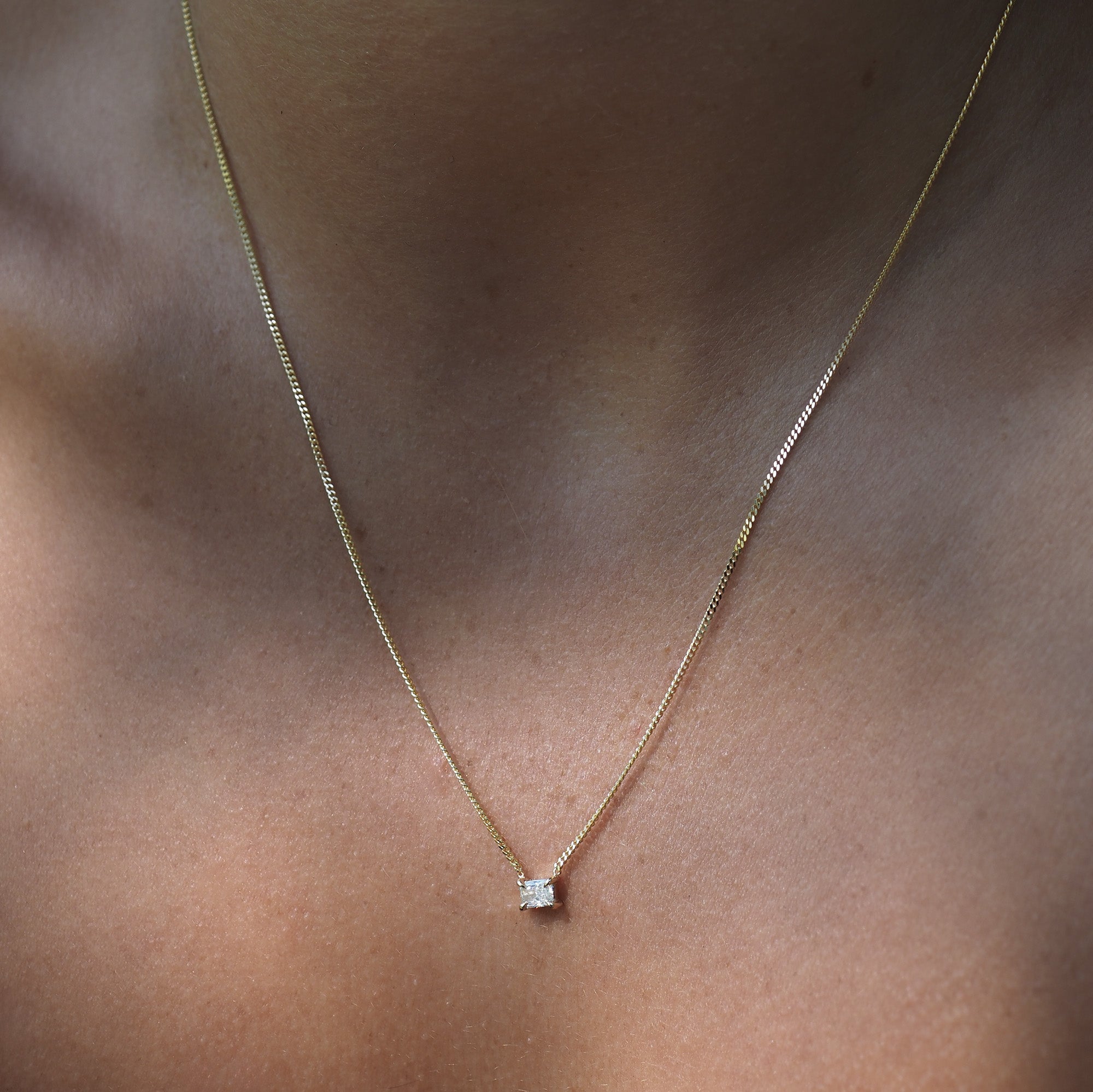The Radiant Diamond Necklace is withheld among a yellow gold chain, with a fixed lab-grown diamond handset within four claws. 