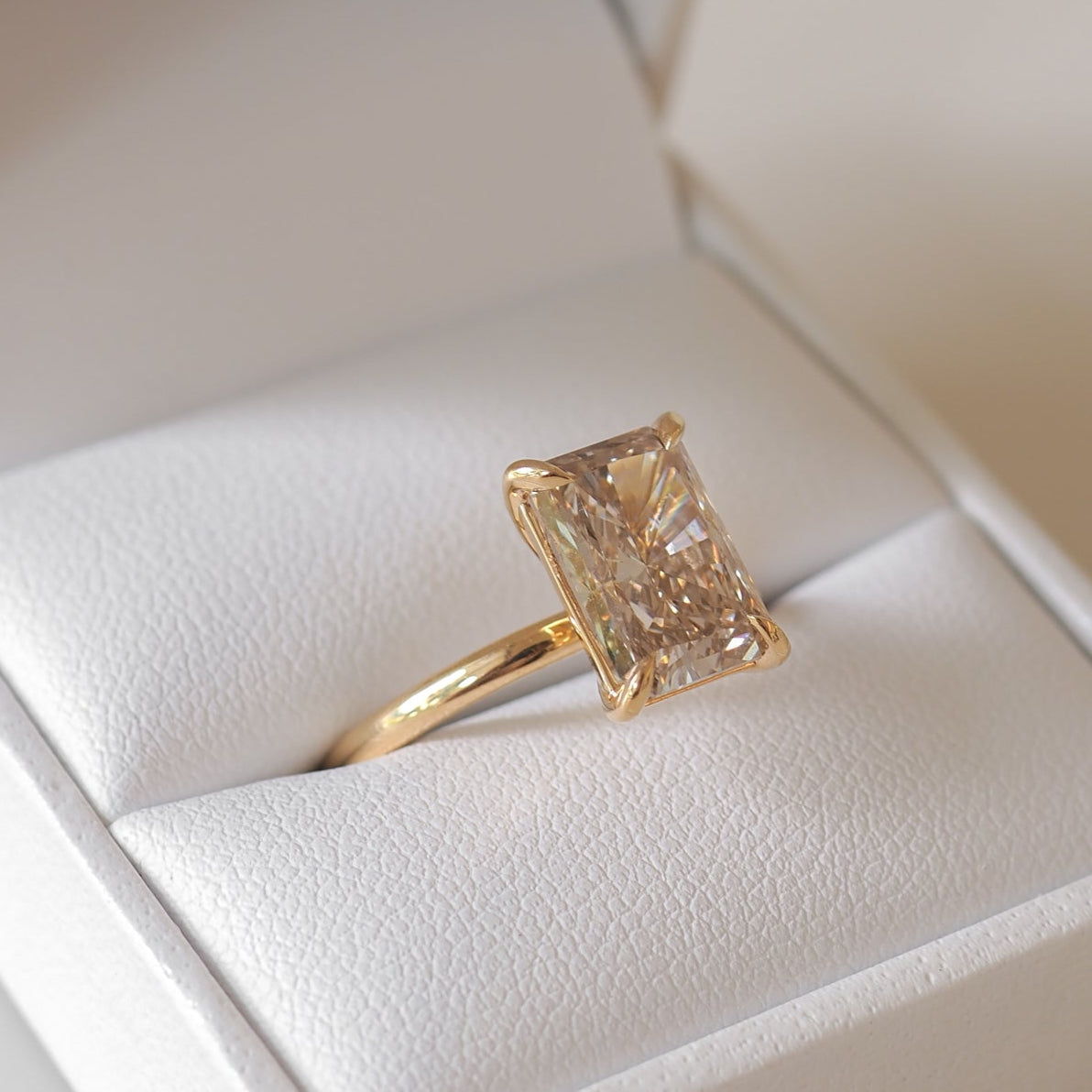 Elegant gold ring with a large rectangular gemstone in an open white box, branded with "Kate & Kole," showcasing luxury jewellery design.