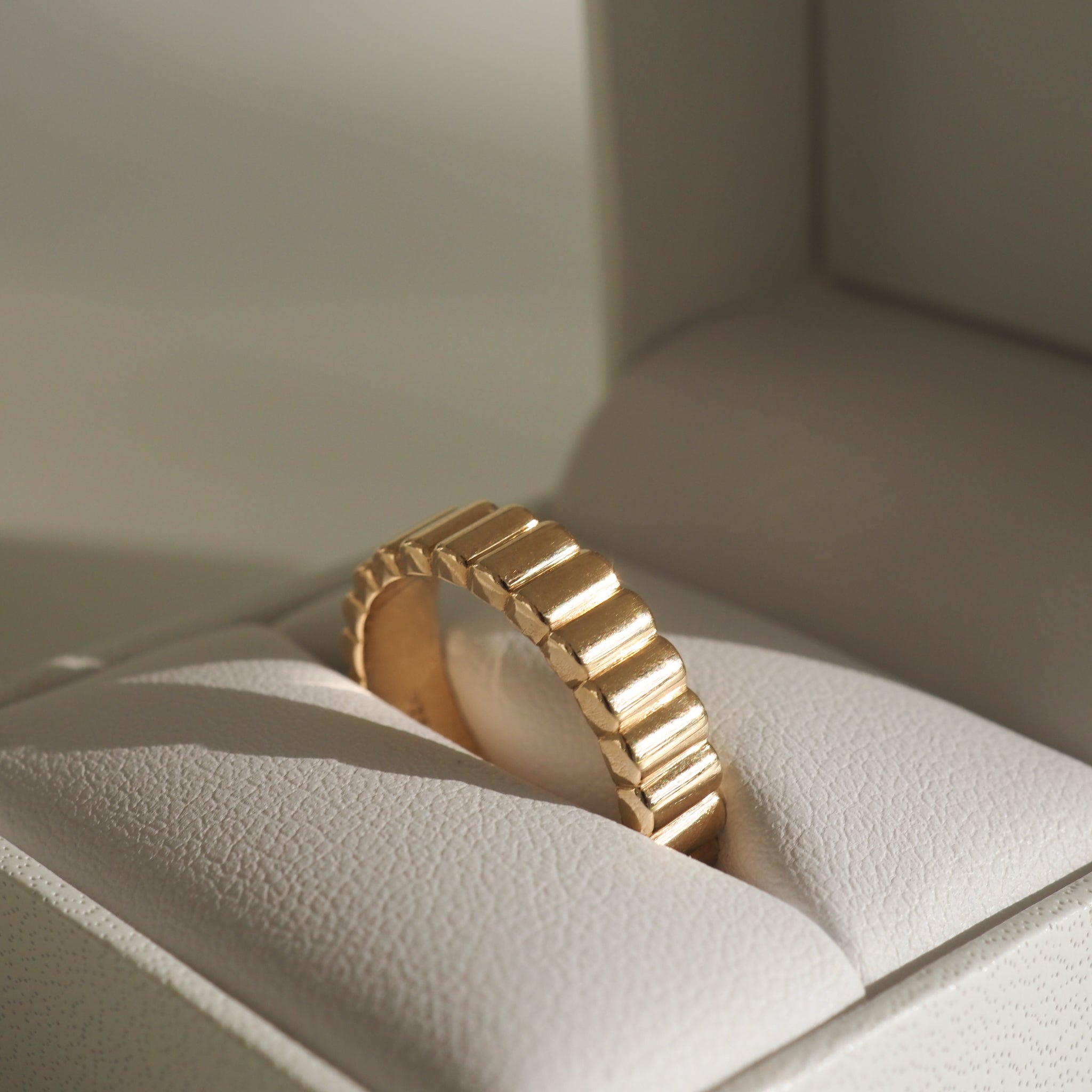 Gold textured ring in an open white jewellery box, highlighting luxury and elegance with its ribbed design. Perfect for high-end Australian jewellery seekers.
