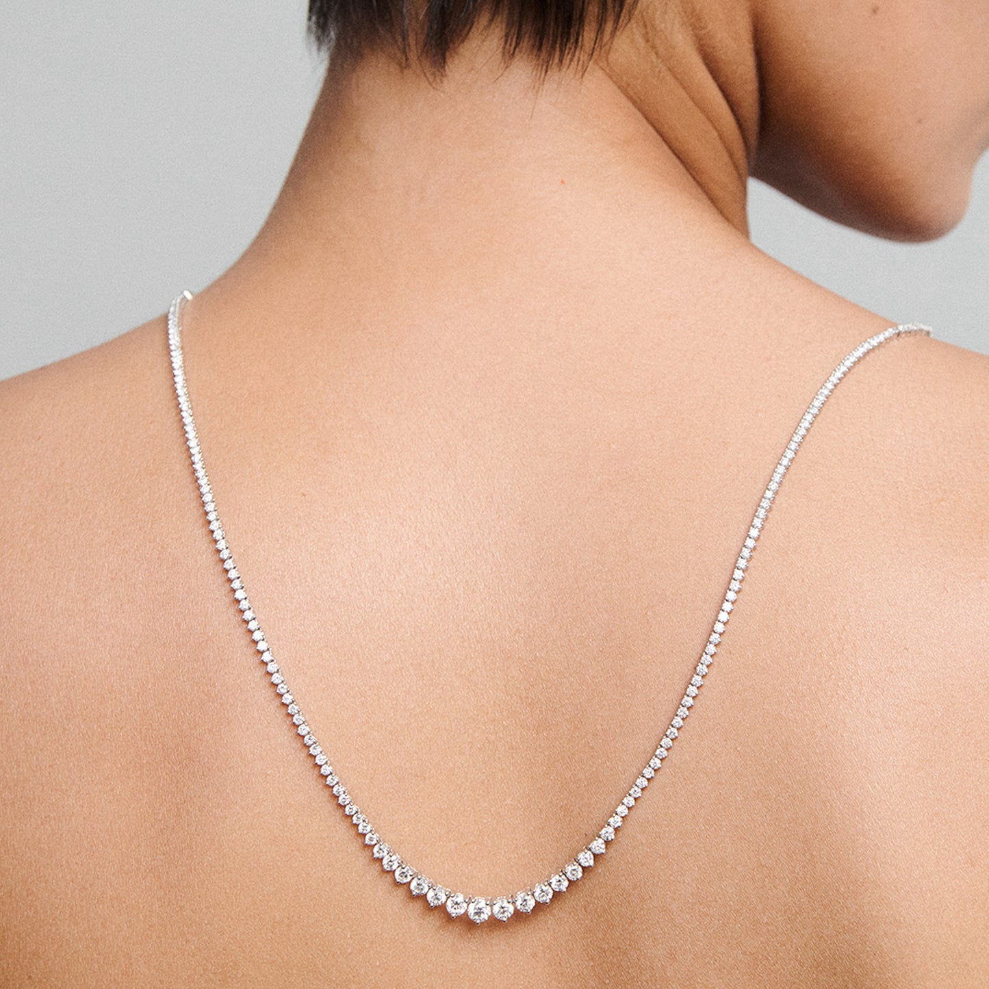 Close-up of a diamond necklace draped elegantly down a woman's bare back, highlighting luxury jewellery design.