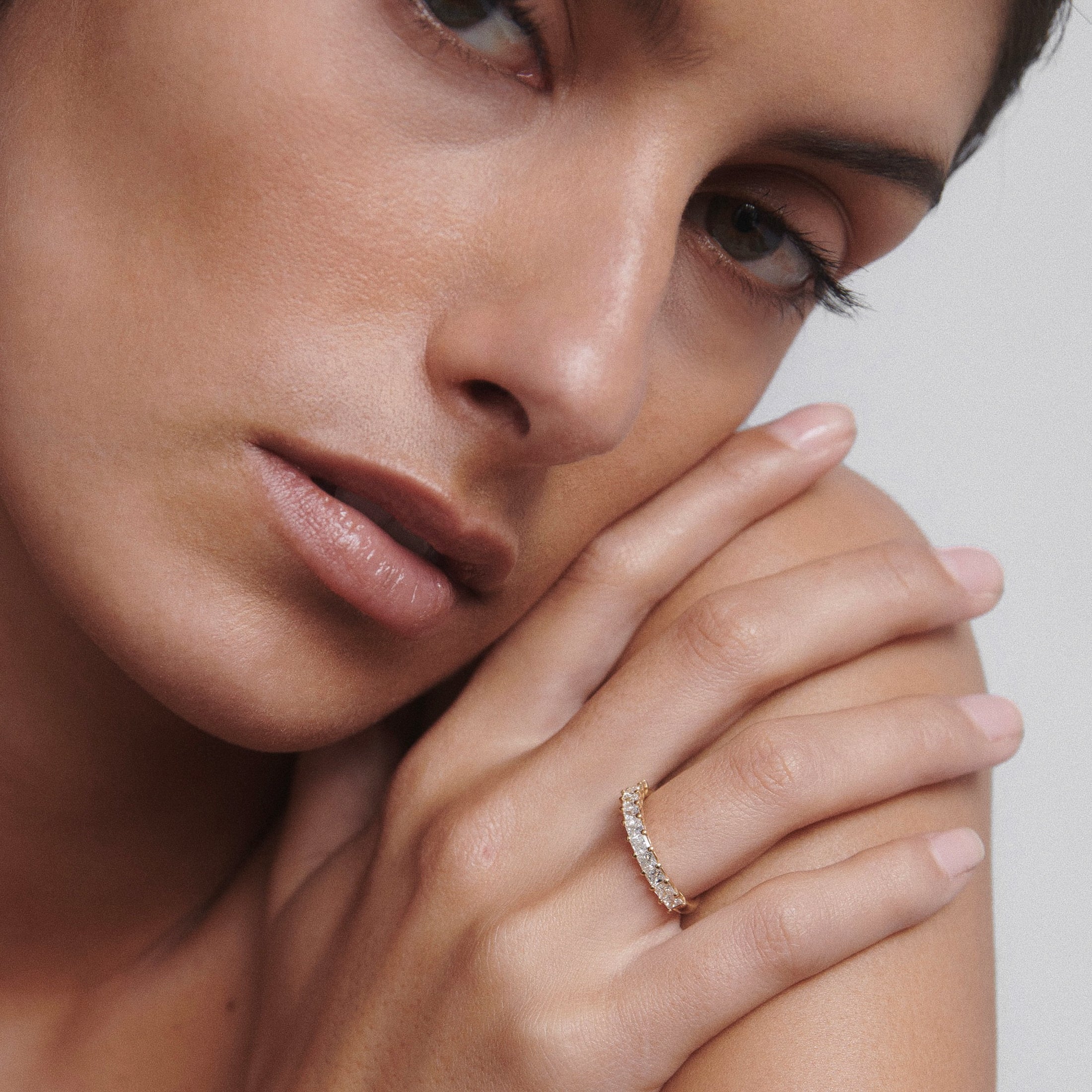 Close-up of a woman showcasing a luxury diamond ring on her finger, highlighting intricate design and elegance. Pale pink manicure is visible.