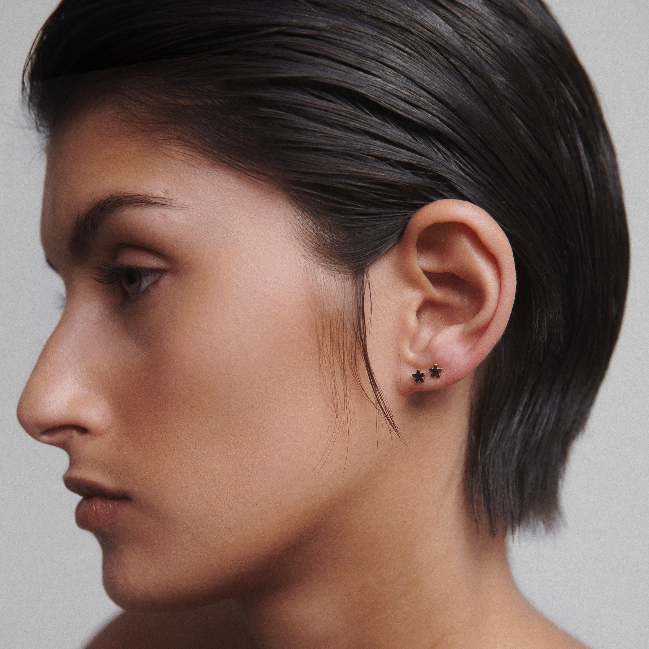 Profile of a person wearing elegant star-shaped stud earrings with sleek hair. Sophisticated and minimalist style.
