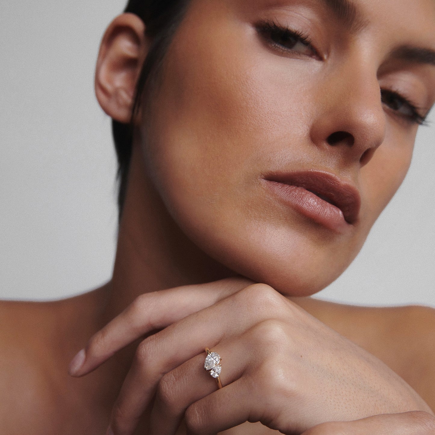 Woman showcasing an elegant diamond ring on her finger. The focus is on the luxurious jewellery, highlighting its brilliance and design.