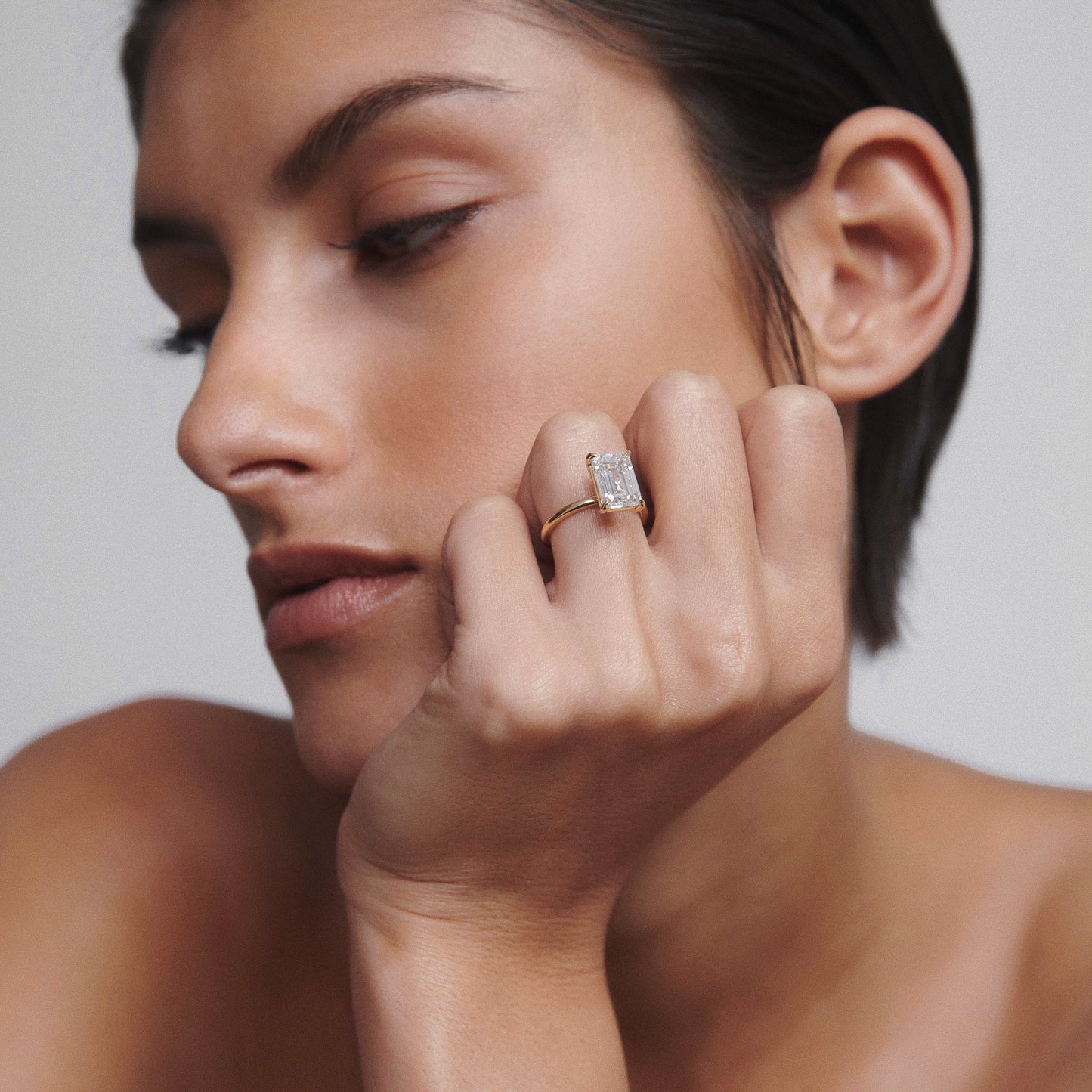 Close-up of a person wearing a large emerald-cut diamond ring on their finger, highlighting luxury jewellery.