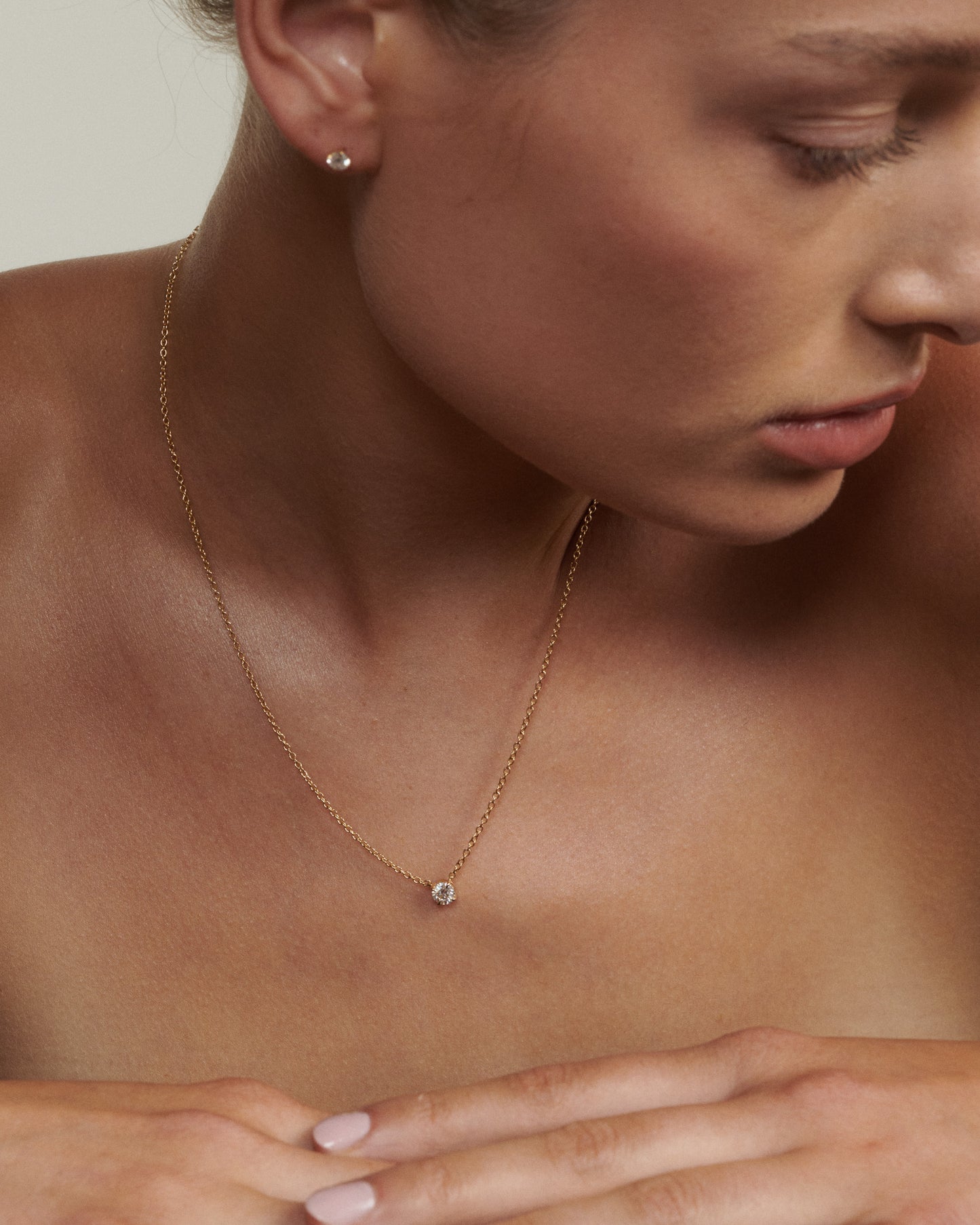 Close-up of a woman wearing a gold necklace with a small pendant.