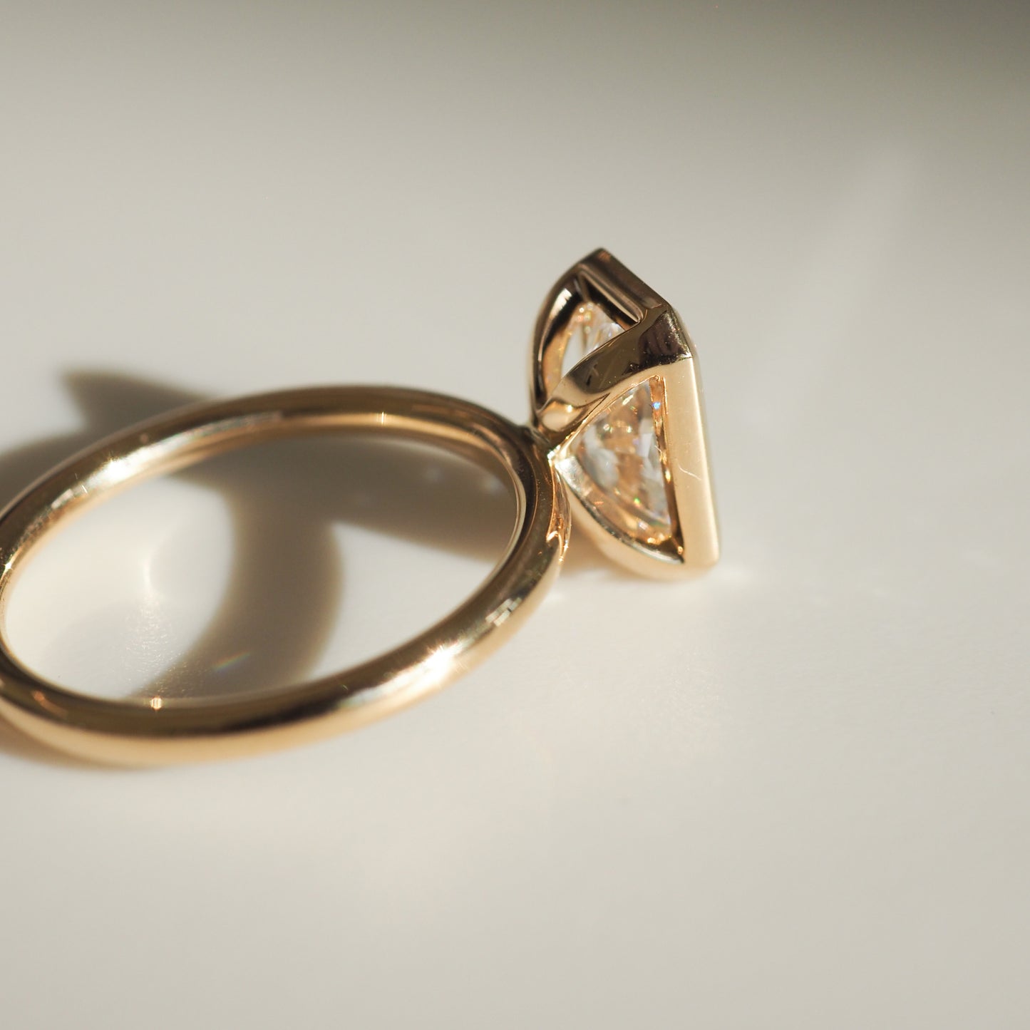 Gold ring with a unique triangular diamond setting, elegantly reflecting light. A luxury jewellery piece perfect for discerning tastes.