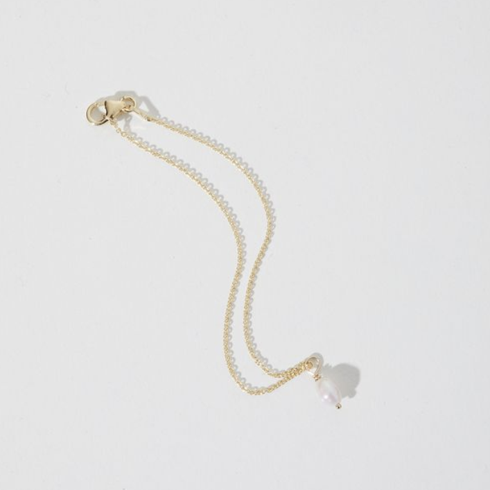 Gold chain bracelet with a delicate white pearl pendant, laid flat on a white background. Elegant and minimalist jewellery design.