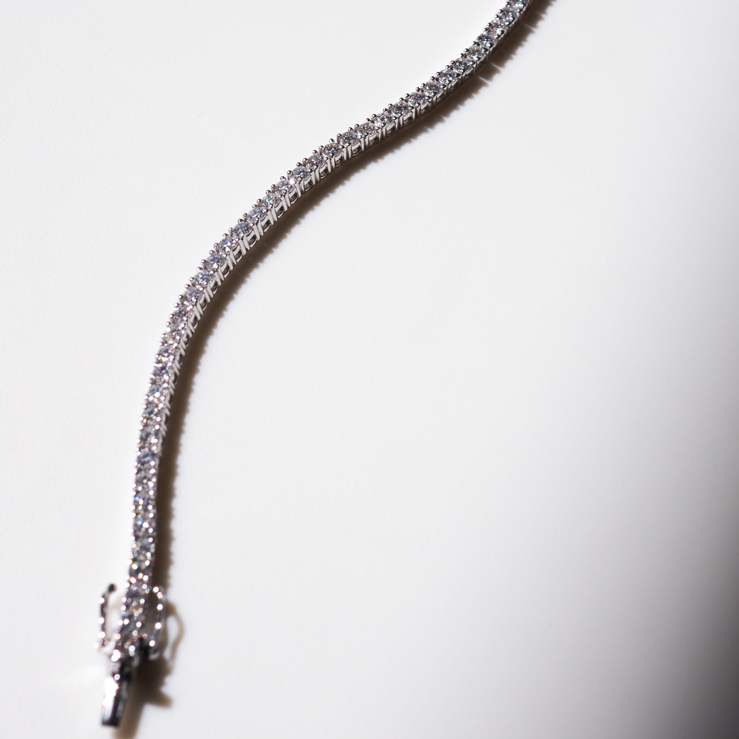 Elegant diamond tennis bracelet on white background, showcasing brilliant sparkling stones and a classic luxury jewellery clasp design.