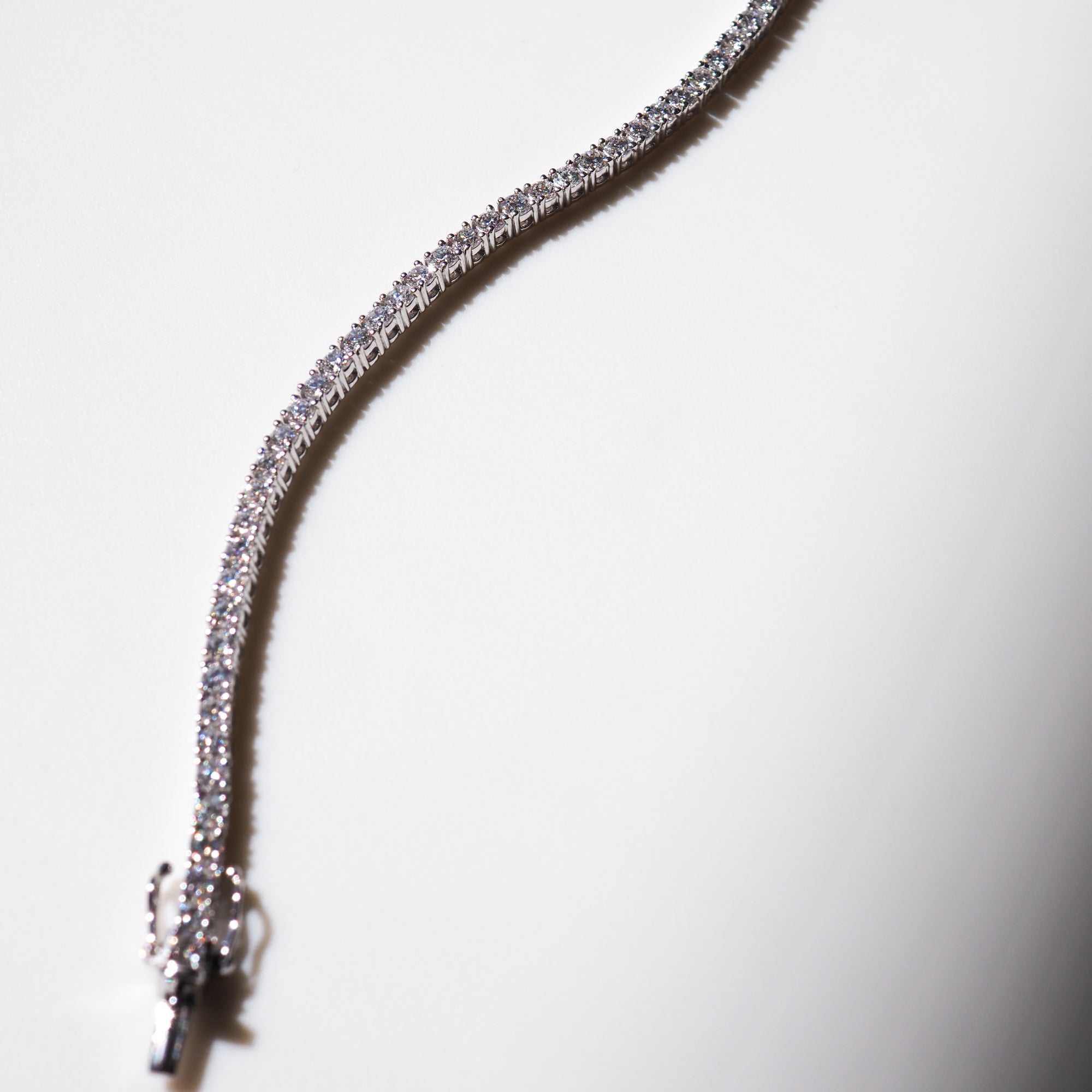 Elegant diamond tennis bracelet on white background, showcasing brilliant sparkling stones and a classic luxury jewellery clasp design.