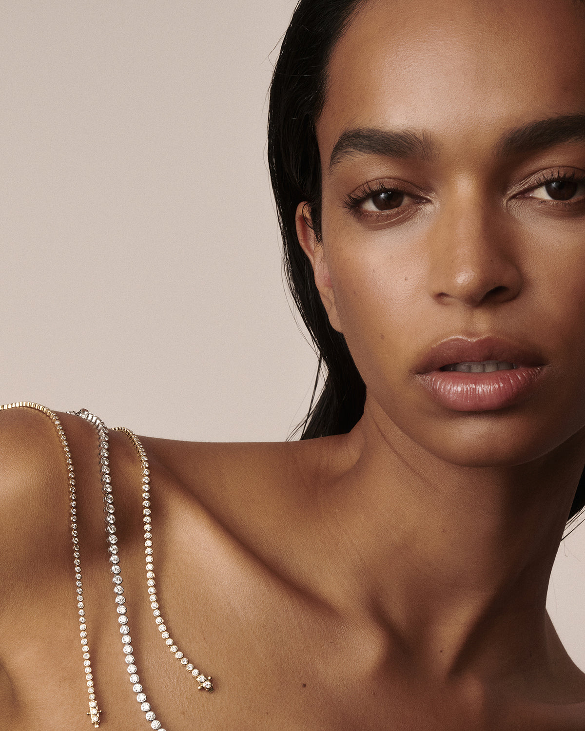 Model wearing yellow gold bezel-set lab-grown diamond tennis jewellery draped over her shoulder by Kate & Kole.