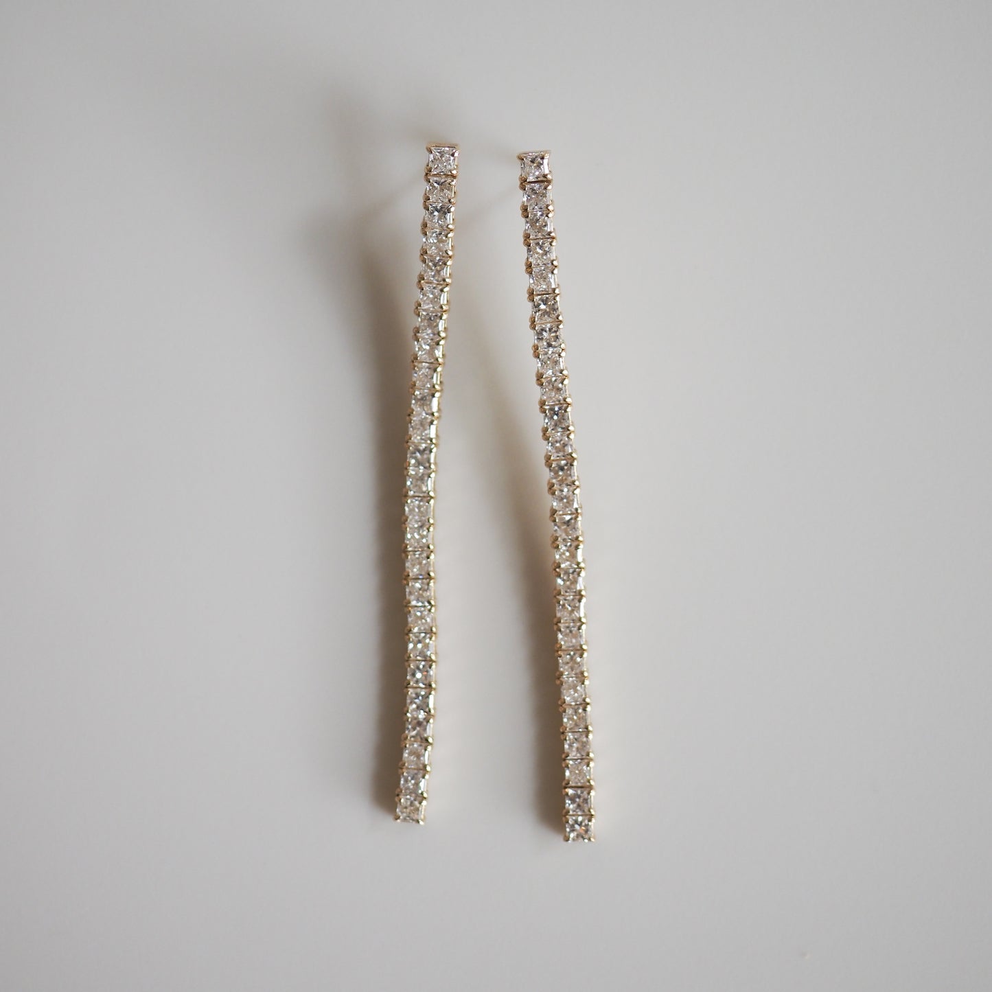 Elegant long diamond earrings on a light background, showcasing luxury jewellery craftsmanship and sparkling stones.