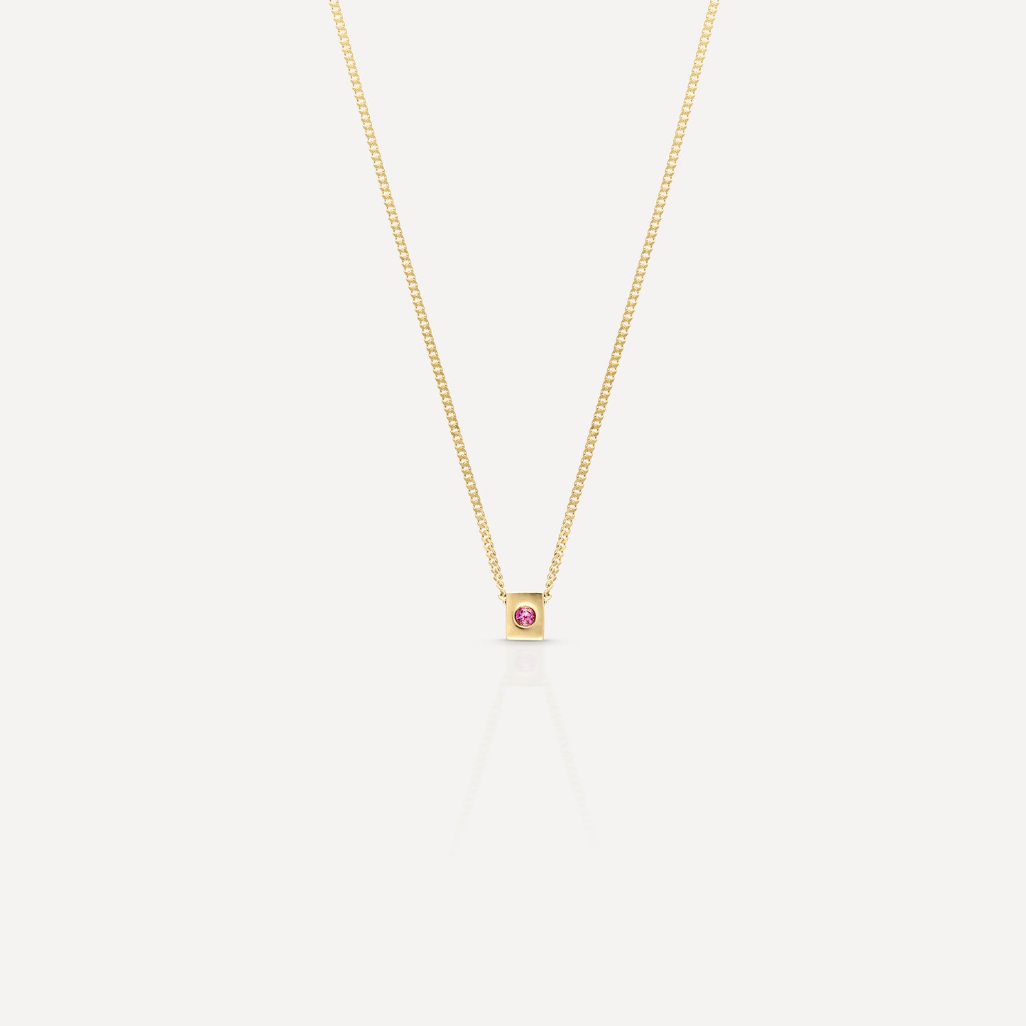 Gold chain necklace featuring a single, small pink gemstone pendant, elegantly designed. Ideal for luxury jewellery collections.