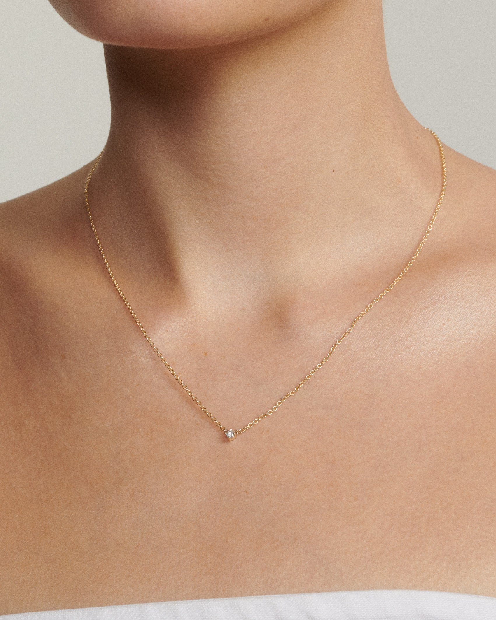 Model wears a gold chain with a tiny diamond fixed to the centre