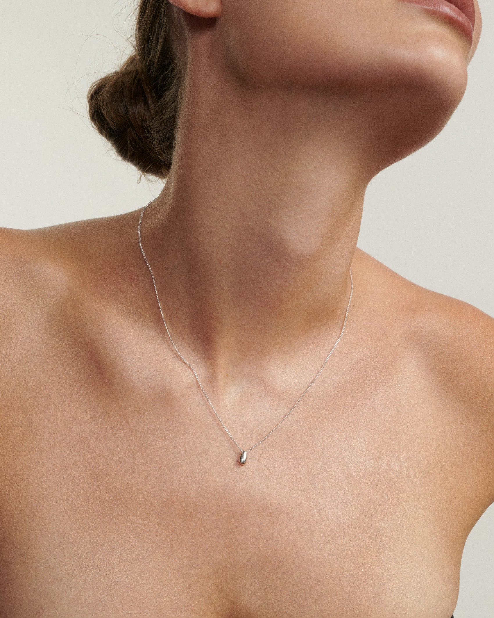 Necklace with a small pendant worn by a person on a neutral background