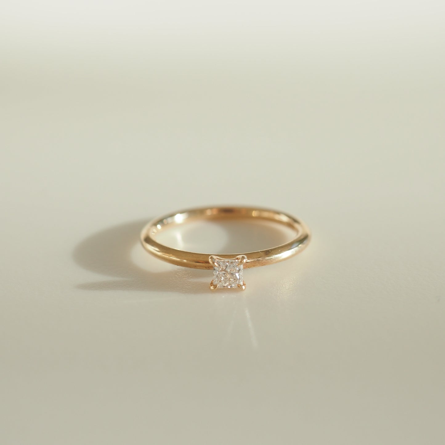 Gold ring with a square-cut diamond set on a light background, showcasing elegance and luxury jewellery design.