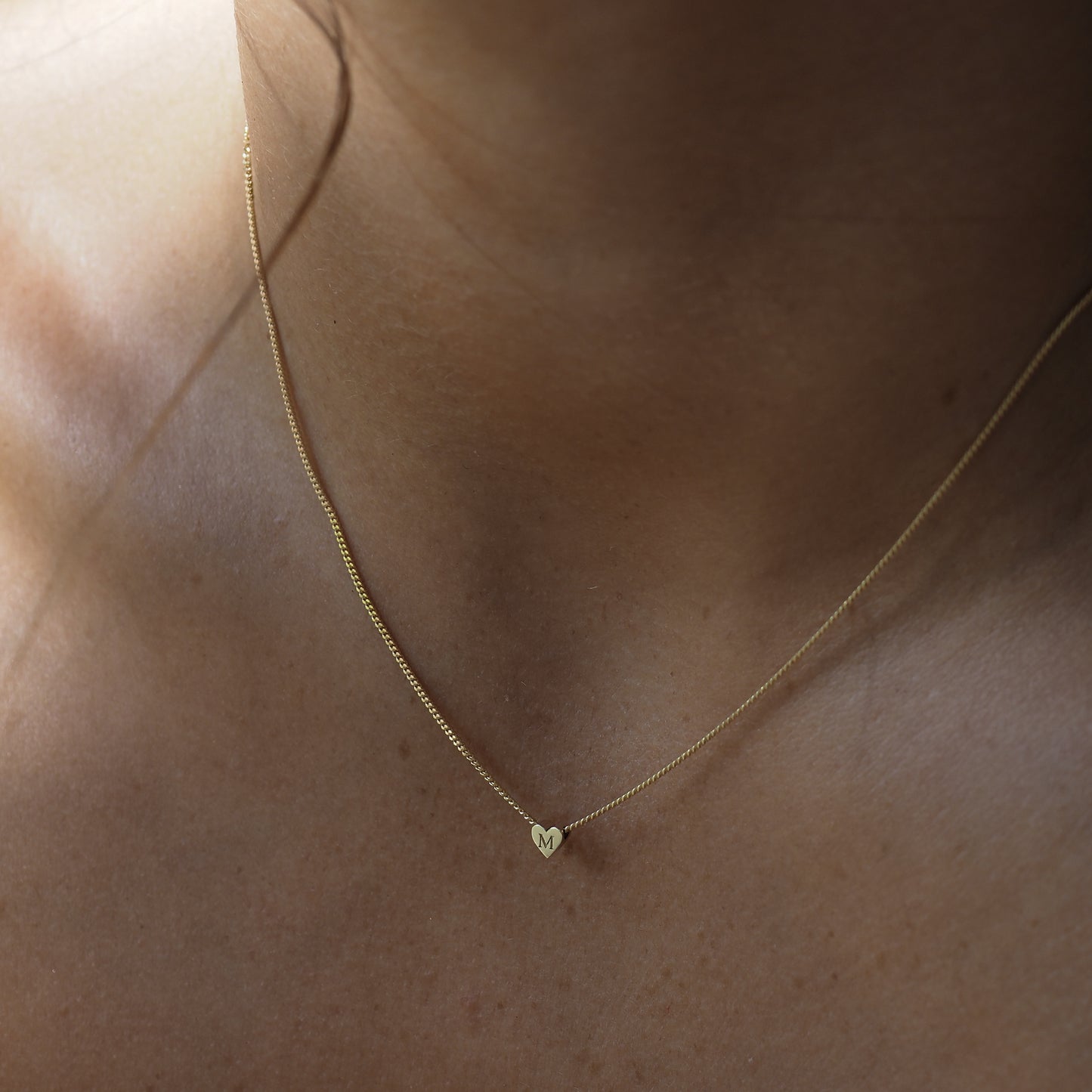 The Tiny Heart Necklace features a single letter engraved in the gold heart fixed in the centre of a yellow gold chain. 