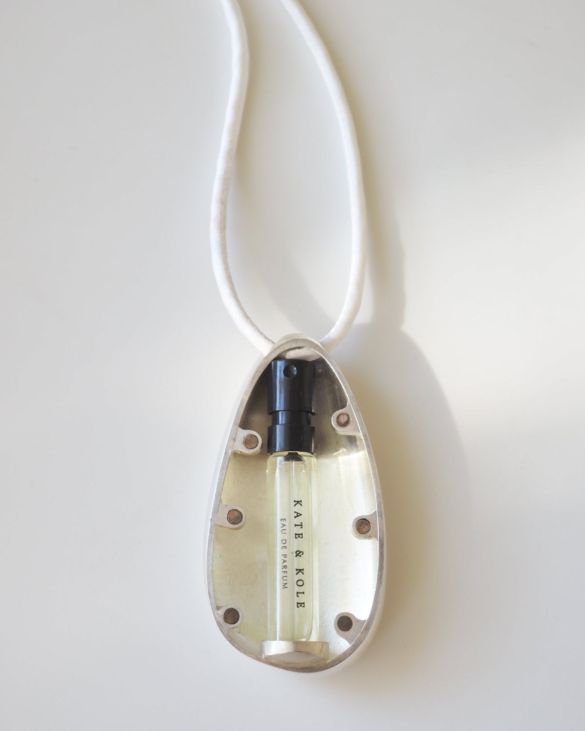 Perfume bottle in a decorative pendant on a white background