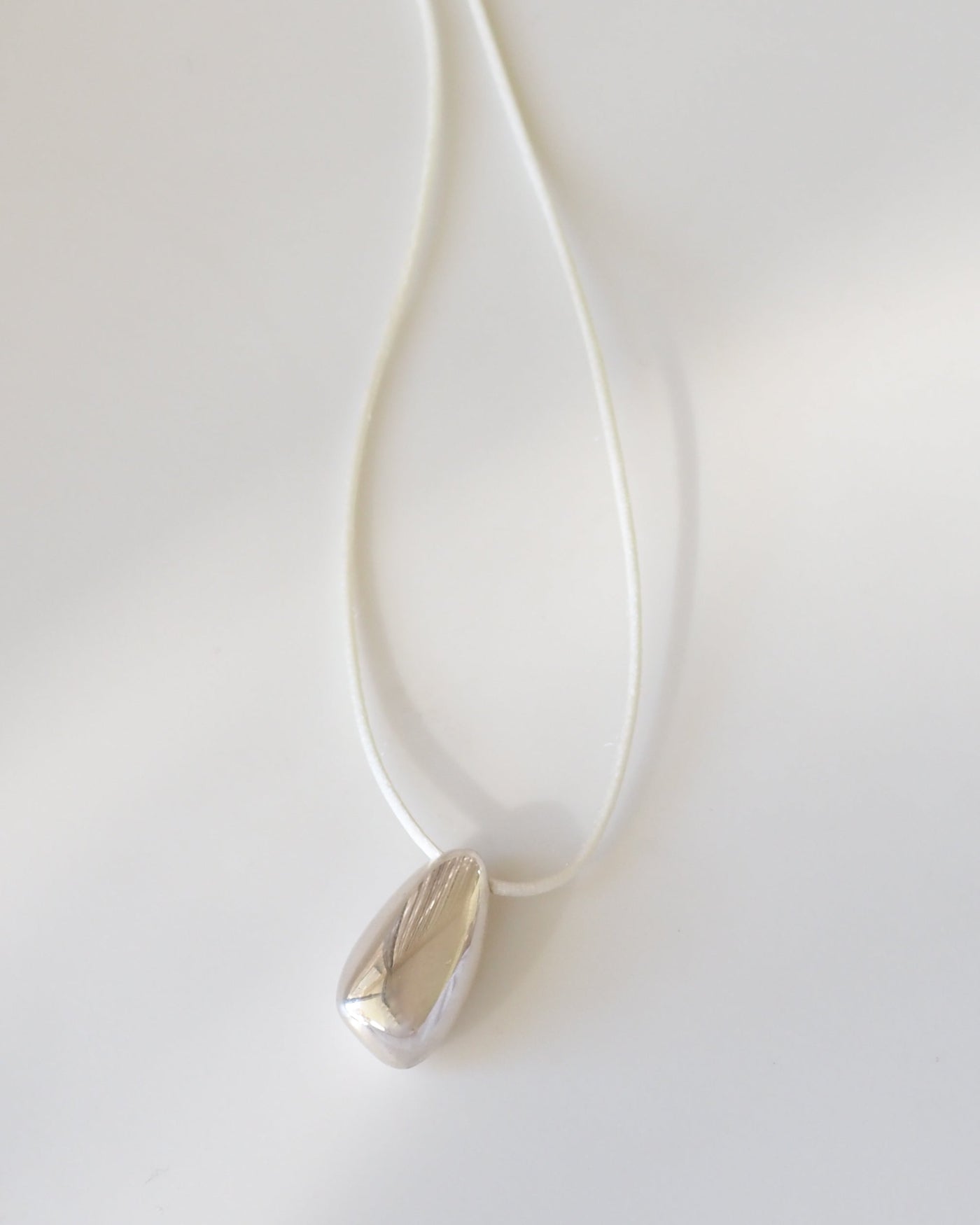 Silver necklace with a teardrop pendant on a white background