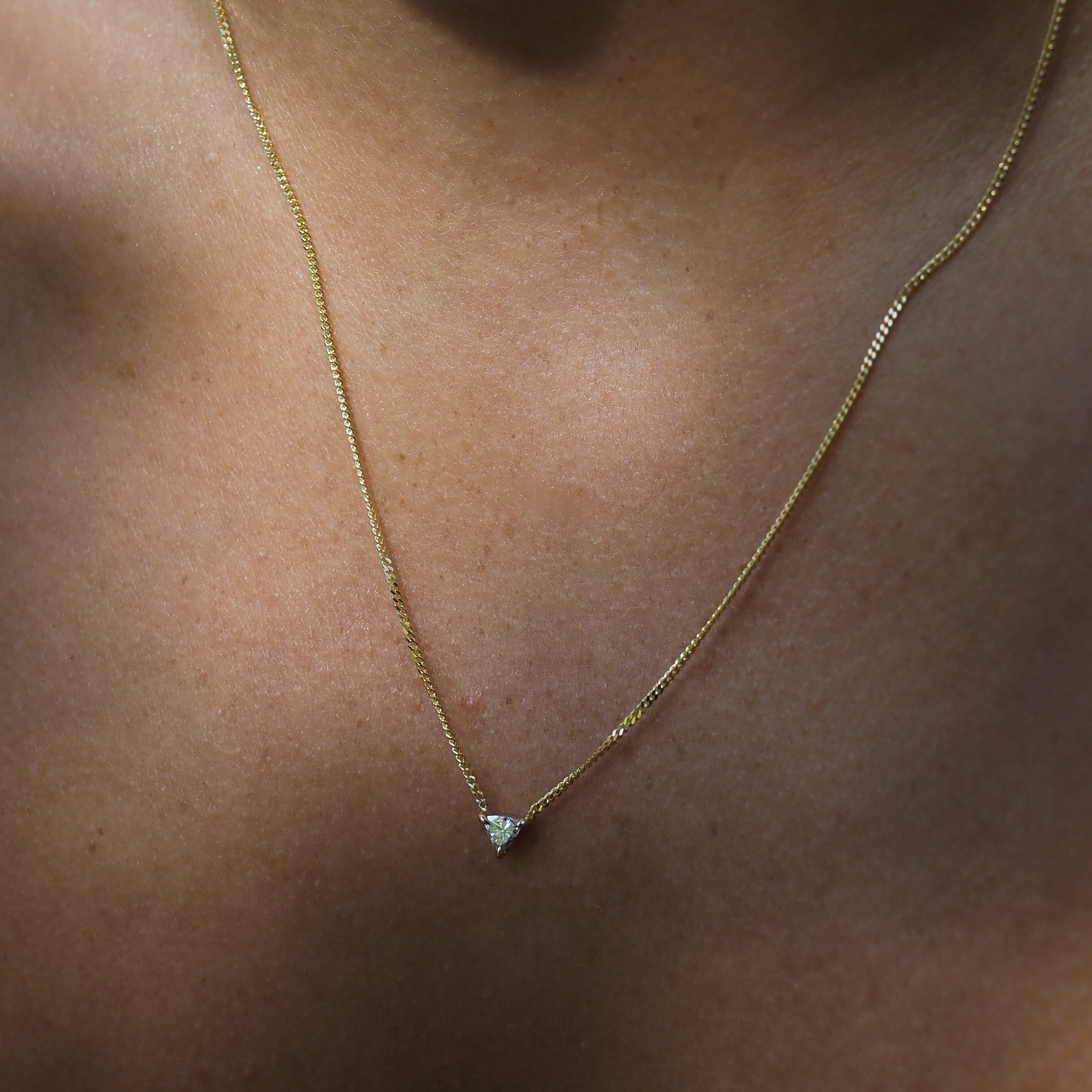 The Trillion Diamond Necklace features a triangular lab-grown diamond fixed on a yellow gold chain, handset within three claws. 