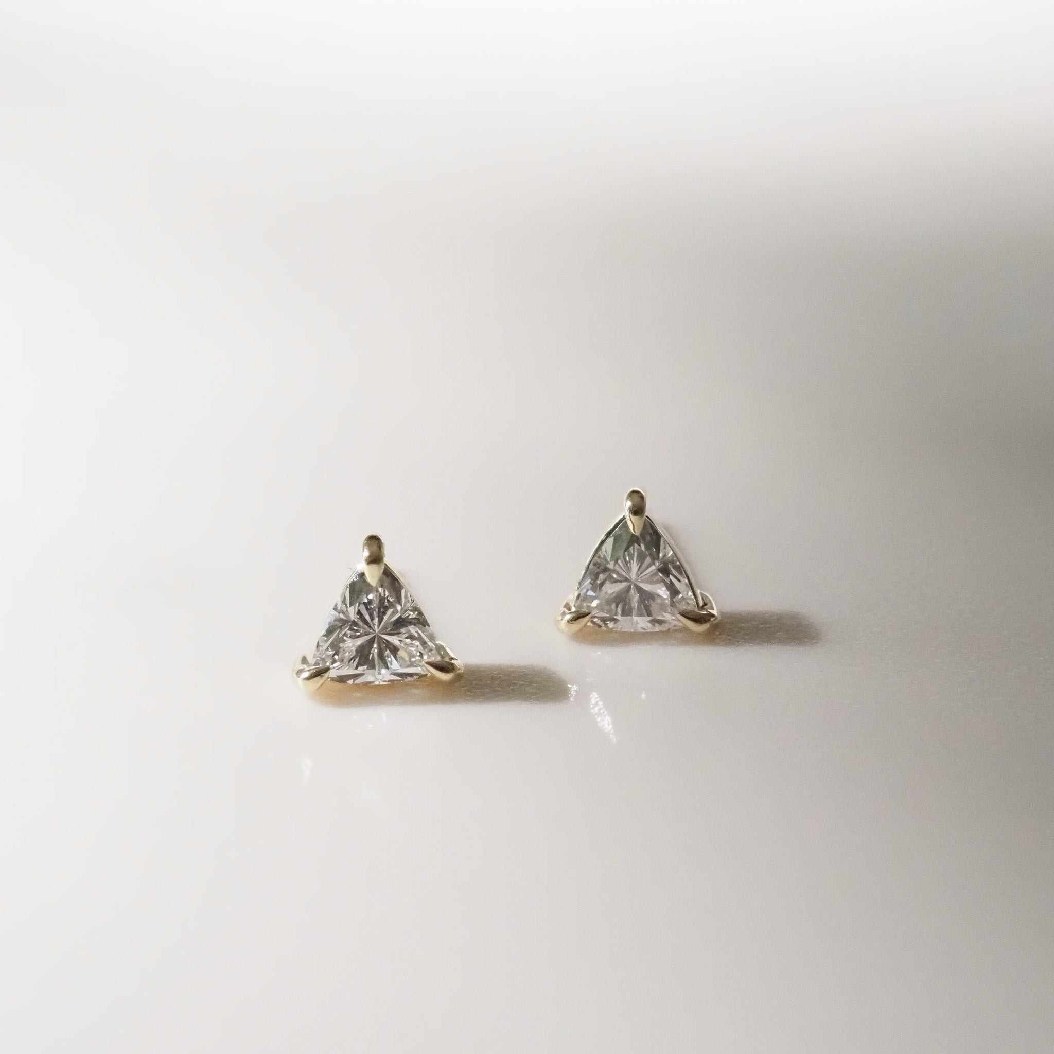 Pair of gold trillion stud earrings on a light gray background