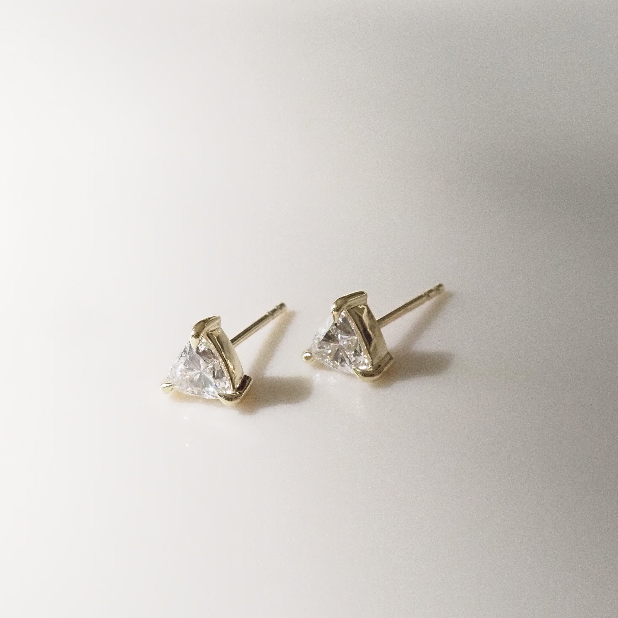 Pair of gold trillion stud earrings on a light gray background