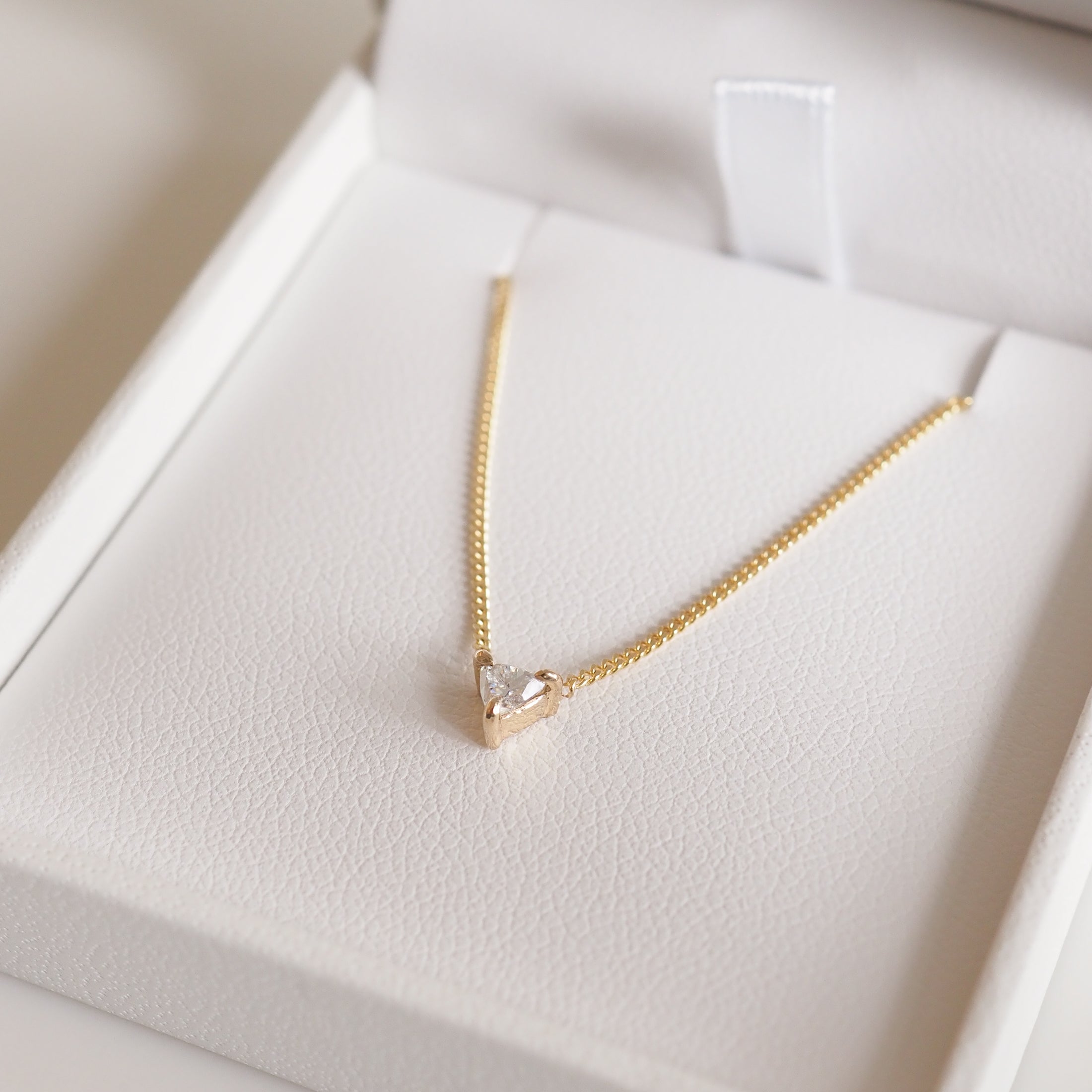 Gold chain necklace with a heart-shaped diamond pendant in a white jewellery box, showcasing luxury and elegance.