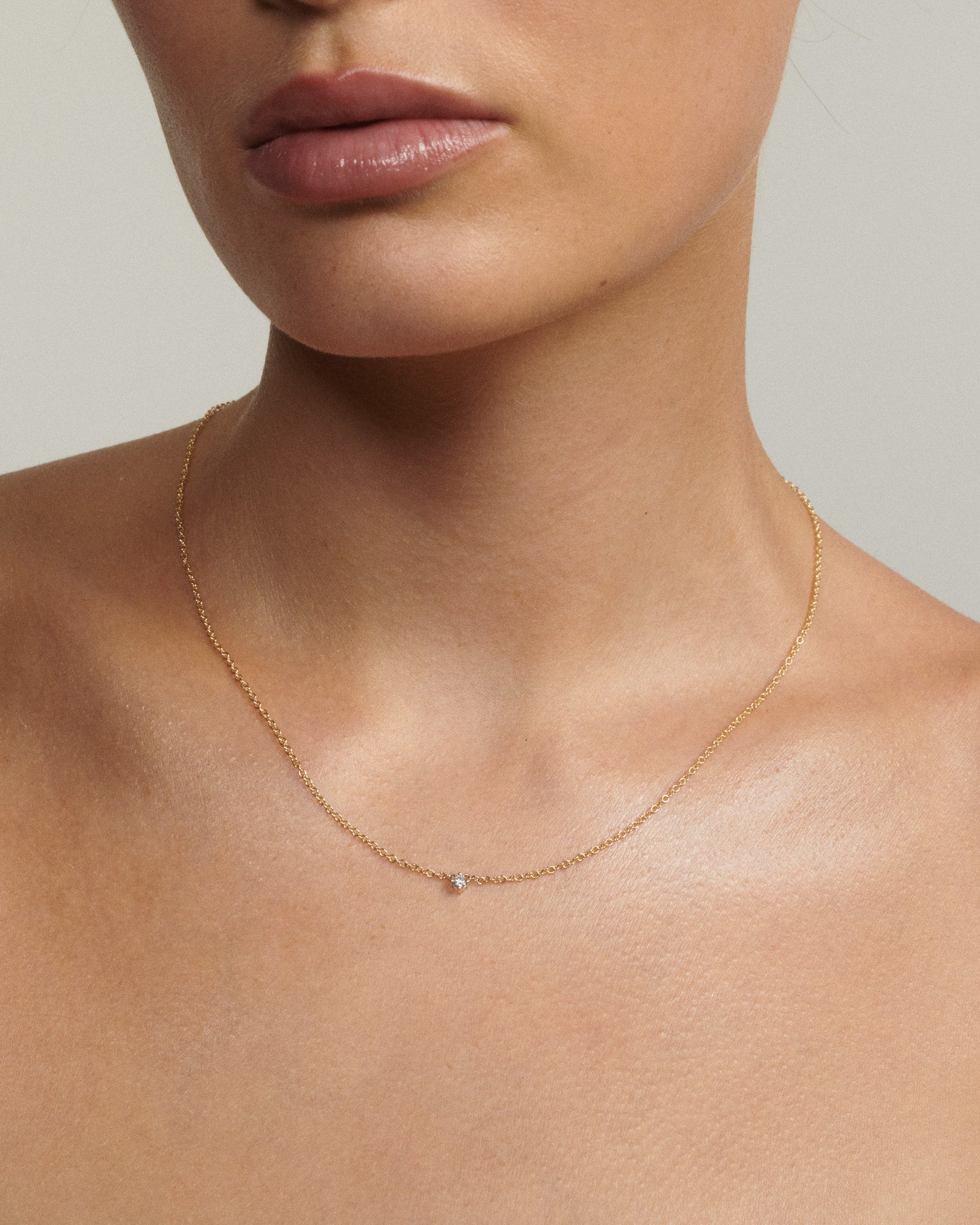 Model wears a gold chain with a tiny diamond fixed to the centre