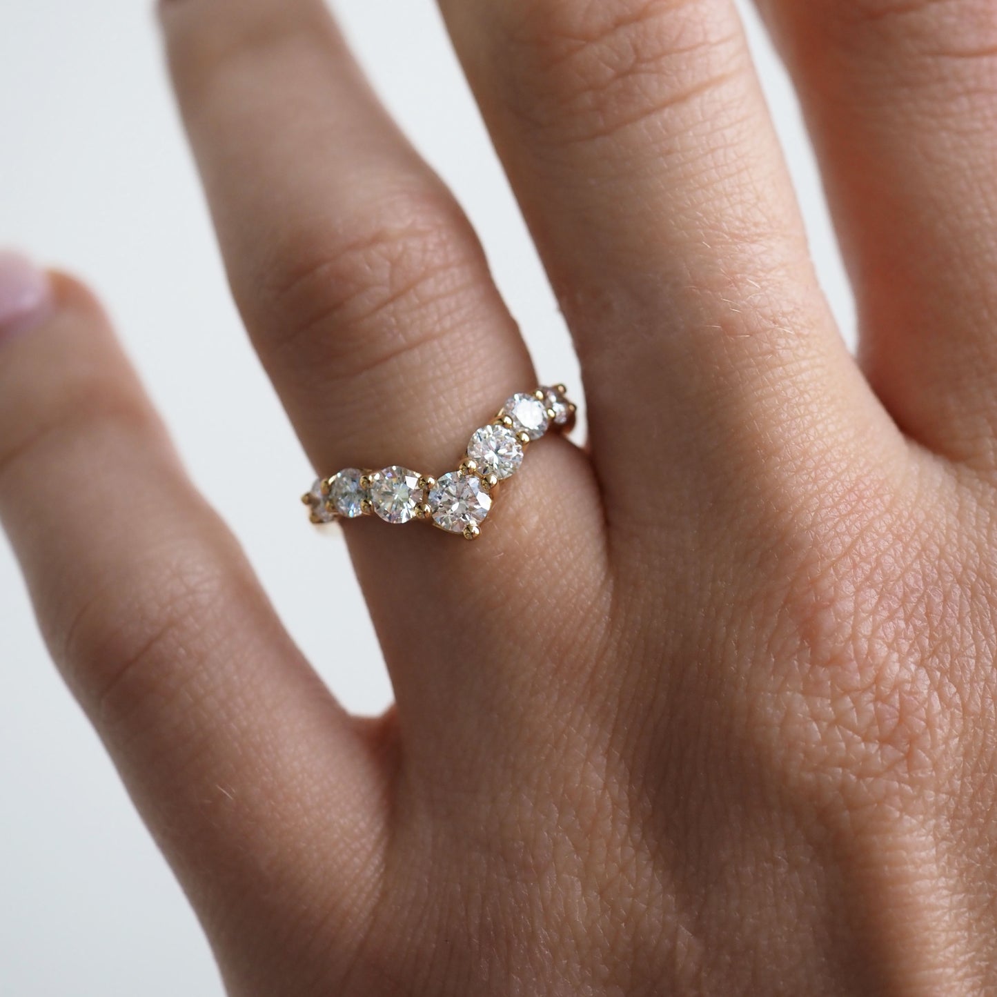 Gold ring with five sparkling white gemstones on a hand. Luxurious jewellery design showcasing elegance and style.