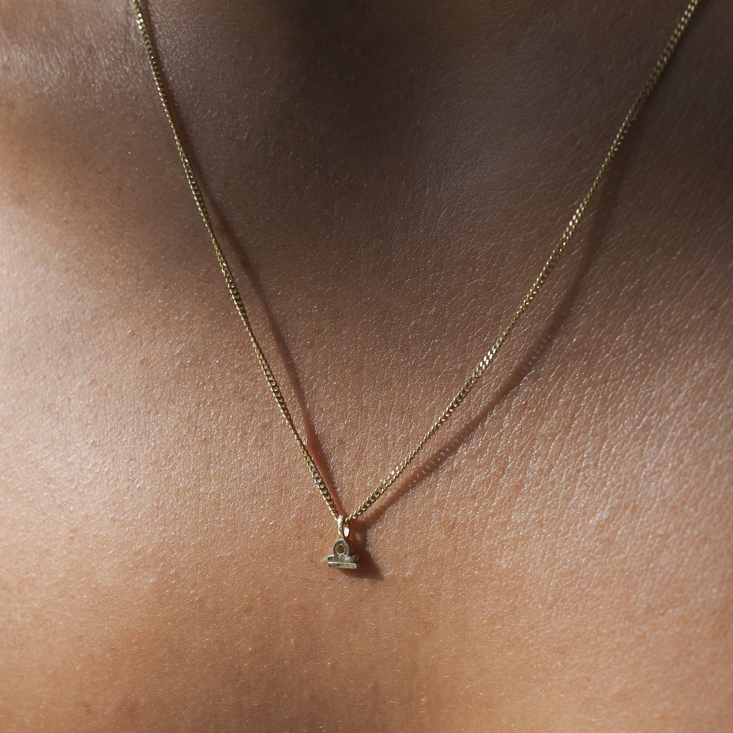The Libra Zodiac Necklace highlights the Libra symbol among a yellow gold chain.