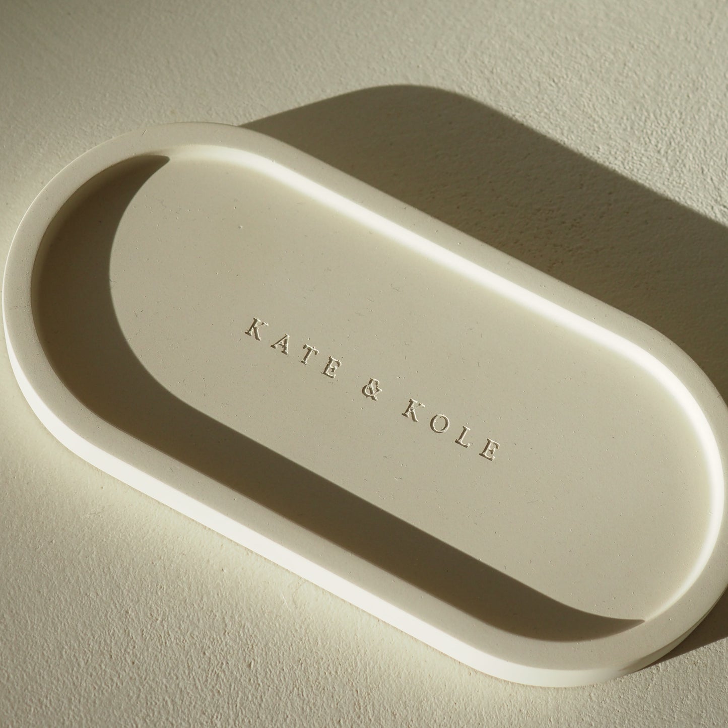 Beige oval tray with 'KATE & KOLE' engraving on a light background