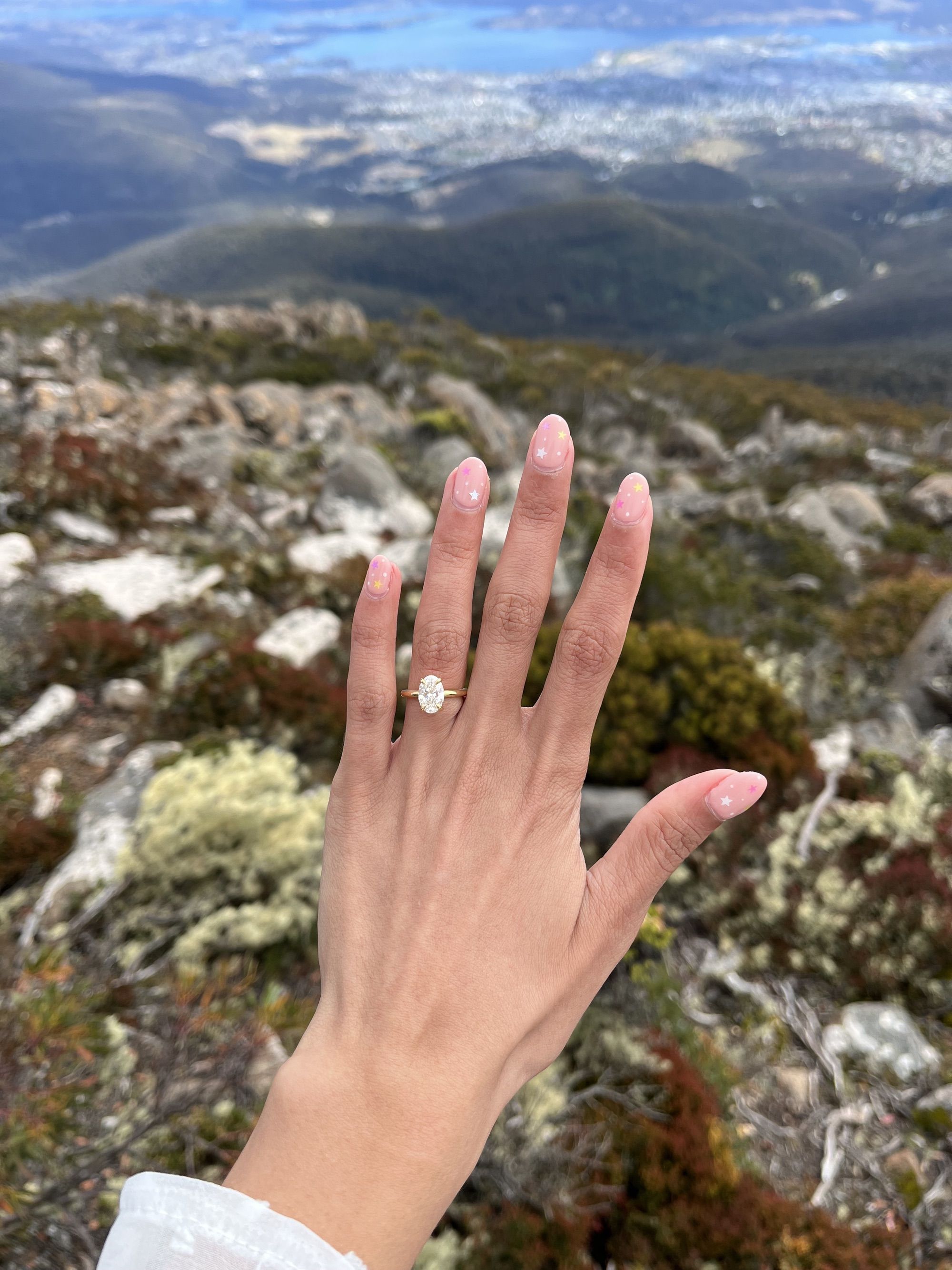 Hand with elegant ring against a scenic mountain backdrop. Perfect for showcasing luxury jewellery in a natural setting.