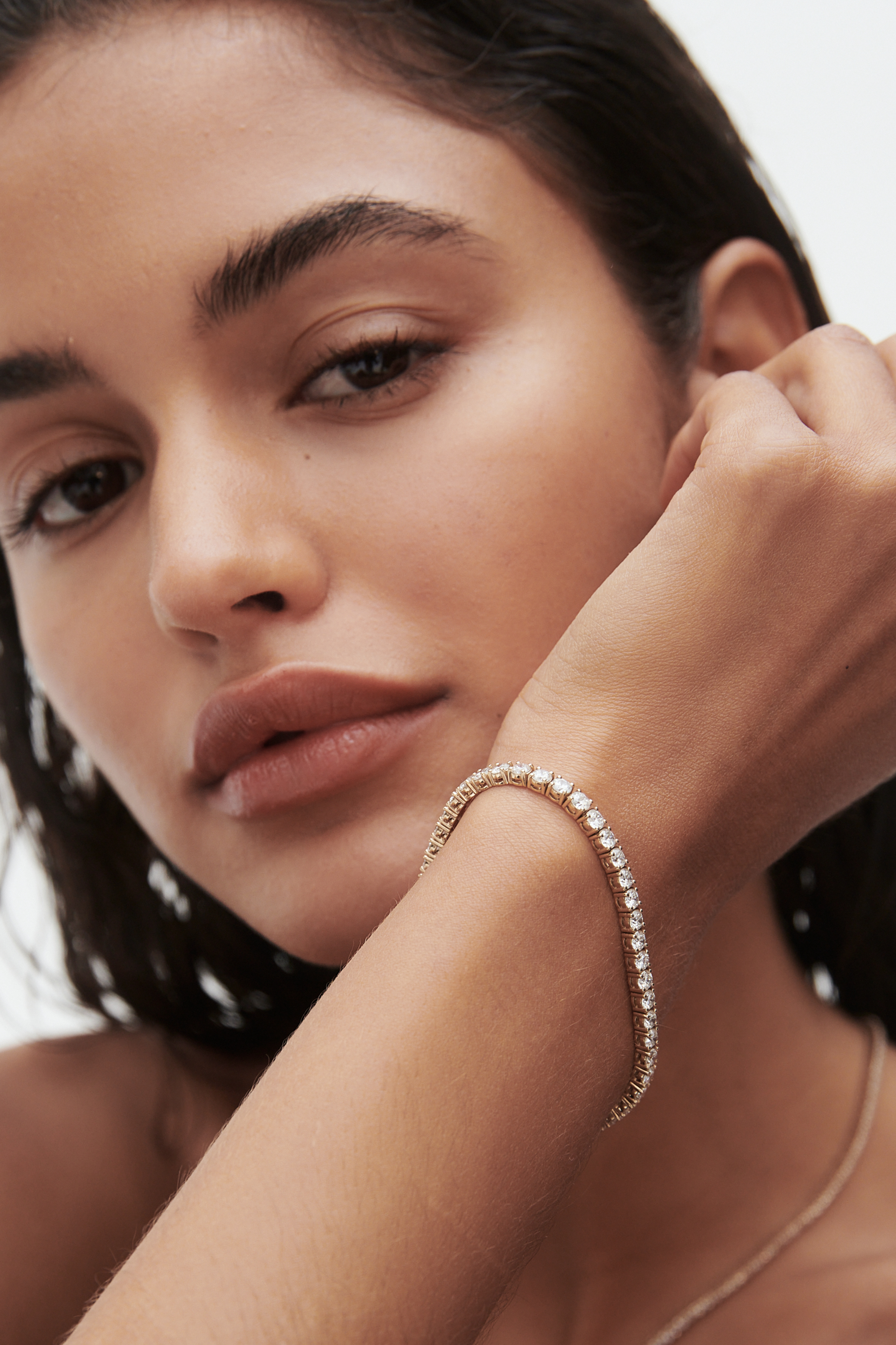Woman with long hair wearing an elegant diamond bracelet; luxury jewellery highlighted against her skin.