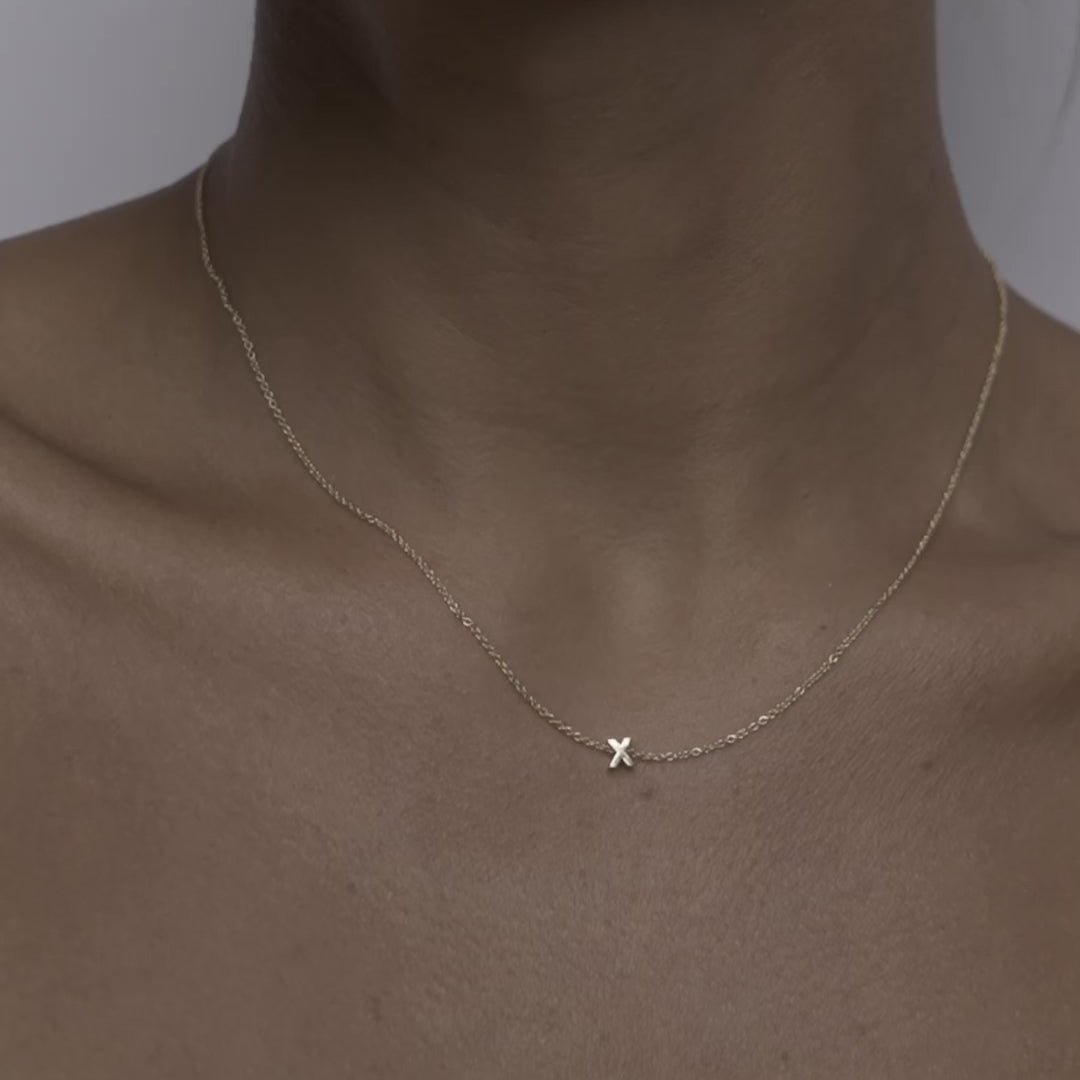 Solid gold and sterling silver jewellery: Close up video of a model wearing our signature 9ct yellow gold Tiny Letter X Charm Necklace on a 40cm cable chain