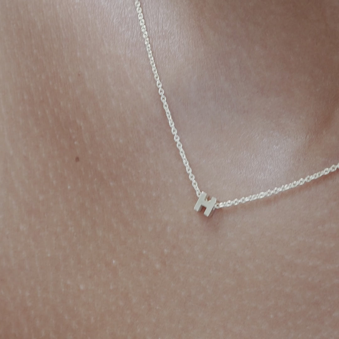 Solid gold and sterling silver jewellery: Video of a model wearing our signature sterling silver tiny letter H charm necklace on a 40cm cable chain