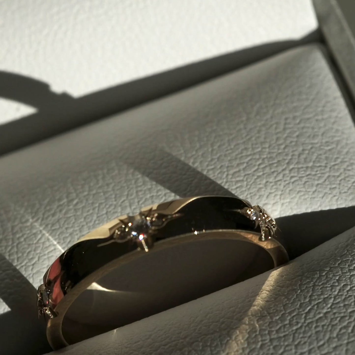 A solid 18ct yellow gold half-round band, set with six tiny trios of speciality set lab-grown diamonds. 3mm thick
