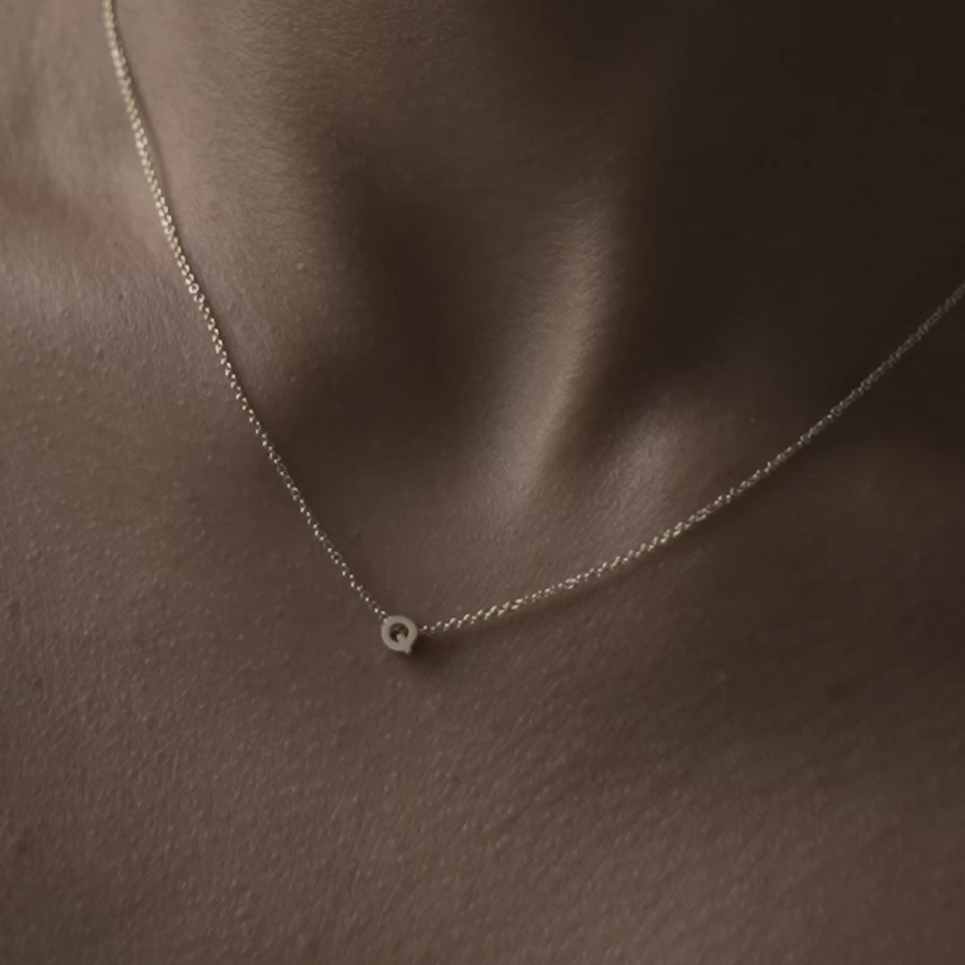 Solid gold and sterling silver jewellery: Close up video of a model wearing our signature 9ct yellow gold Tiny Letter Q Charm Necklace on a 40cm cable chain