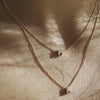High quality, hand-finished jewellery: Video of a model layering two 9ct Yellow Gold Diamond Letter Charm Necklaces in a 40cm and 45cm length, drenched in sunlight