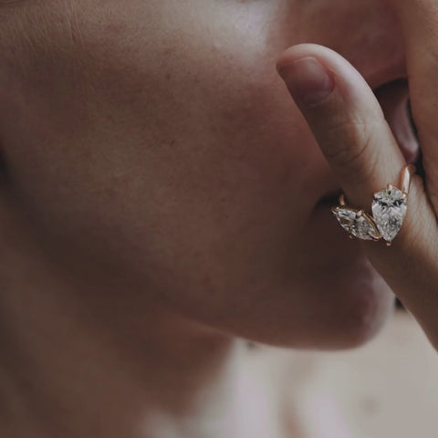 A person with a diamond ring on their finger, touching their face.