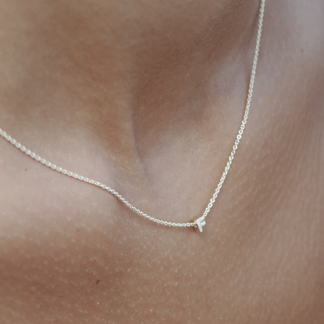 Solid gold and sterling silver jewellery: Video of a model wearing our signature sterling silver tiny letter F charm necklace on a 40cm cable chain