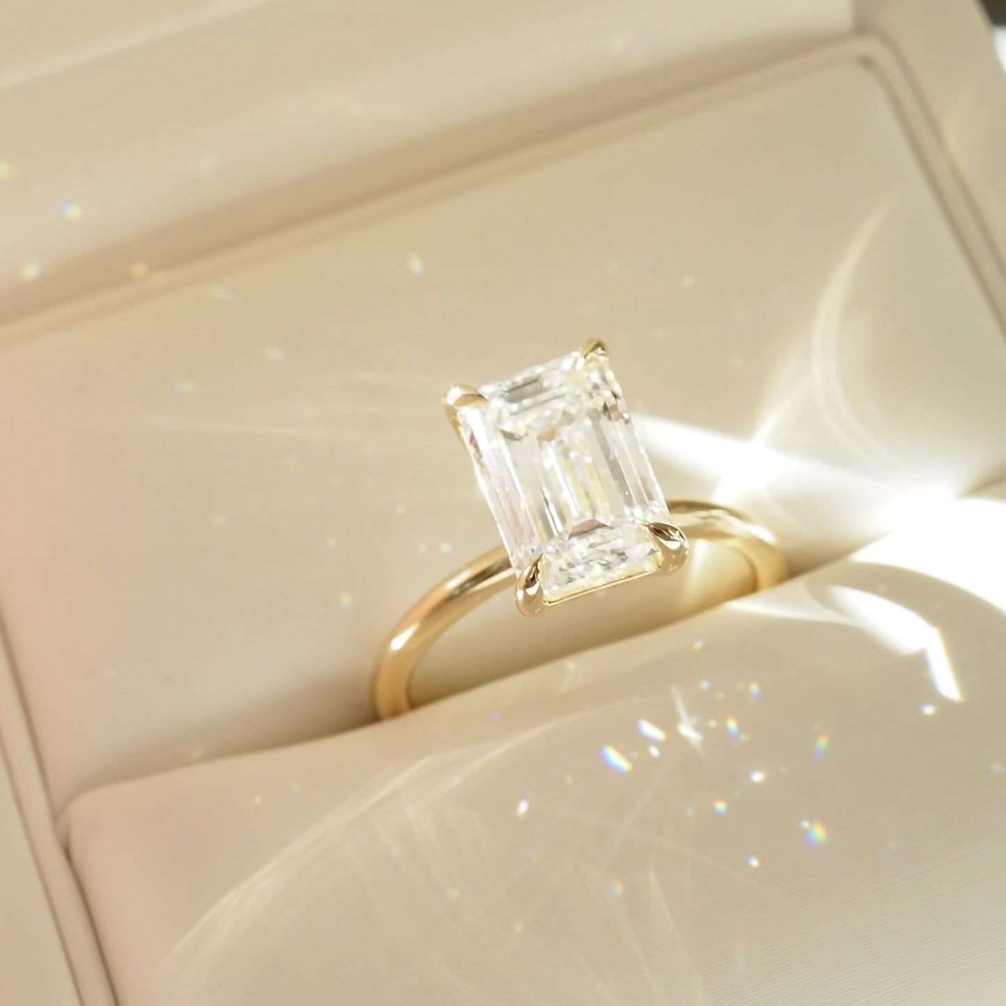 Emerald cut diamond ring with a gold band in a cream box. Luxurious, elegant jewellery design.