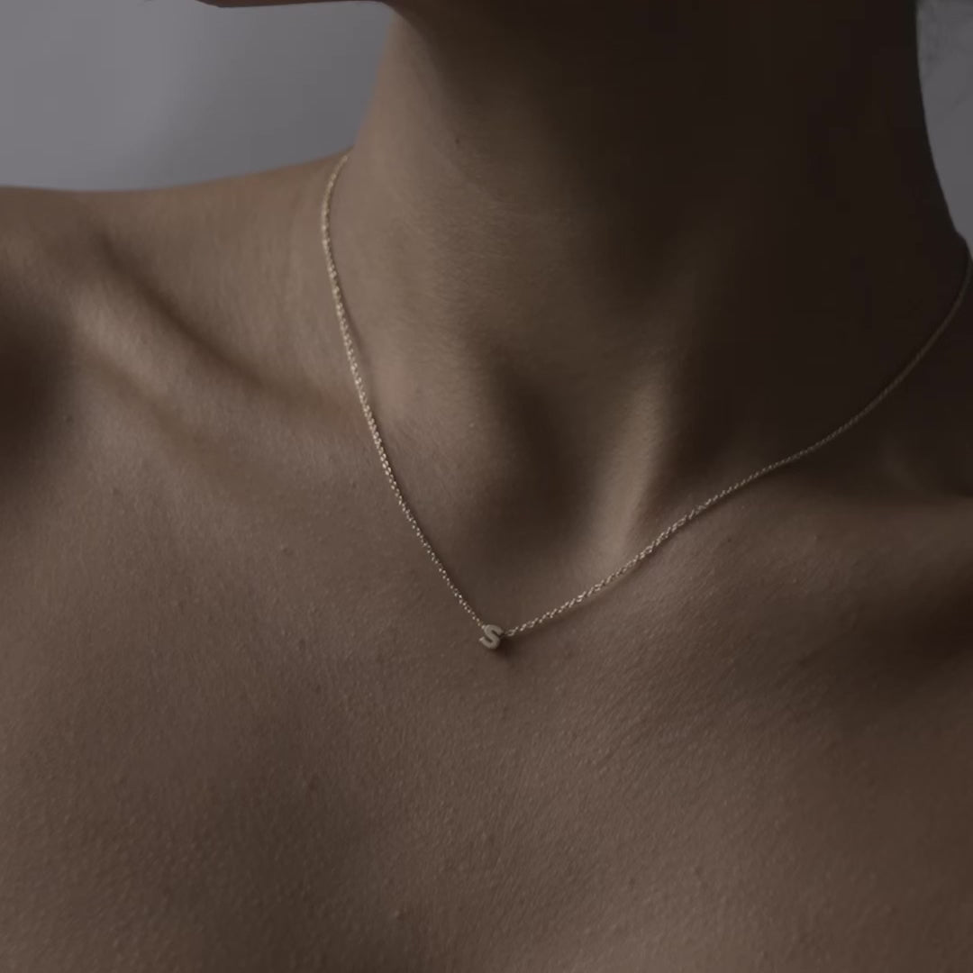 Solid gold and sterling silver jewellery: Close up video of a model wearing our signature 9ct yellow gold Tiny Letter S Charm Necklace on a 40cm cable chain