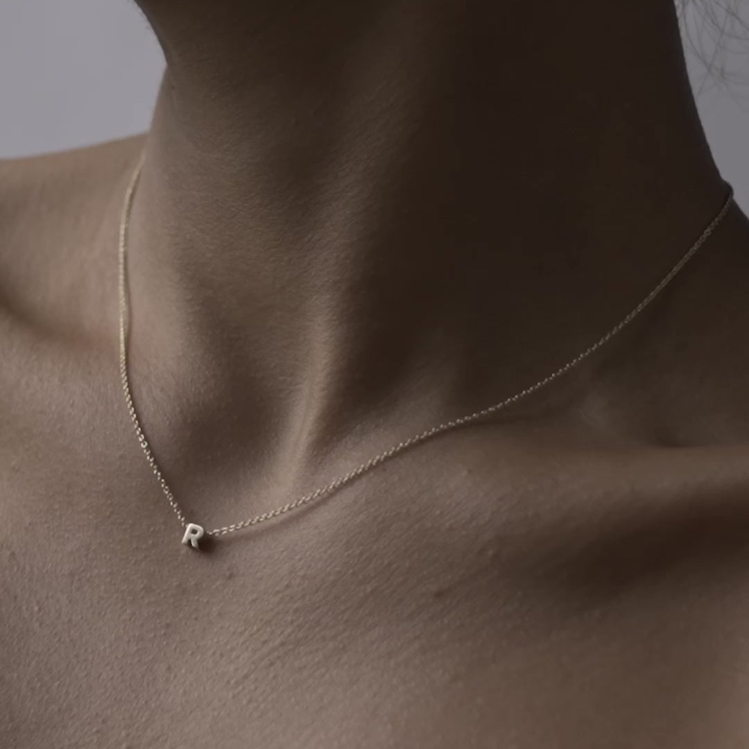 Solid gold and sterling silver jewellery: Close up video of a model wearing our signature 9ct yellow gold Tiny Letter R Charm Necklace on a 40cm cable chain