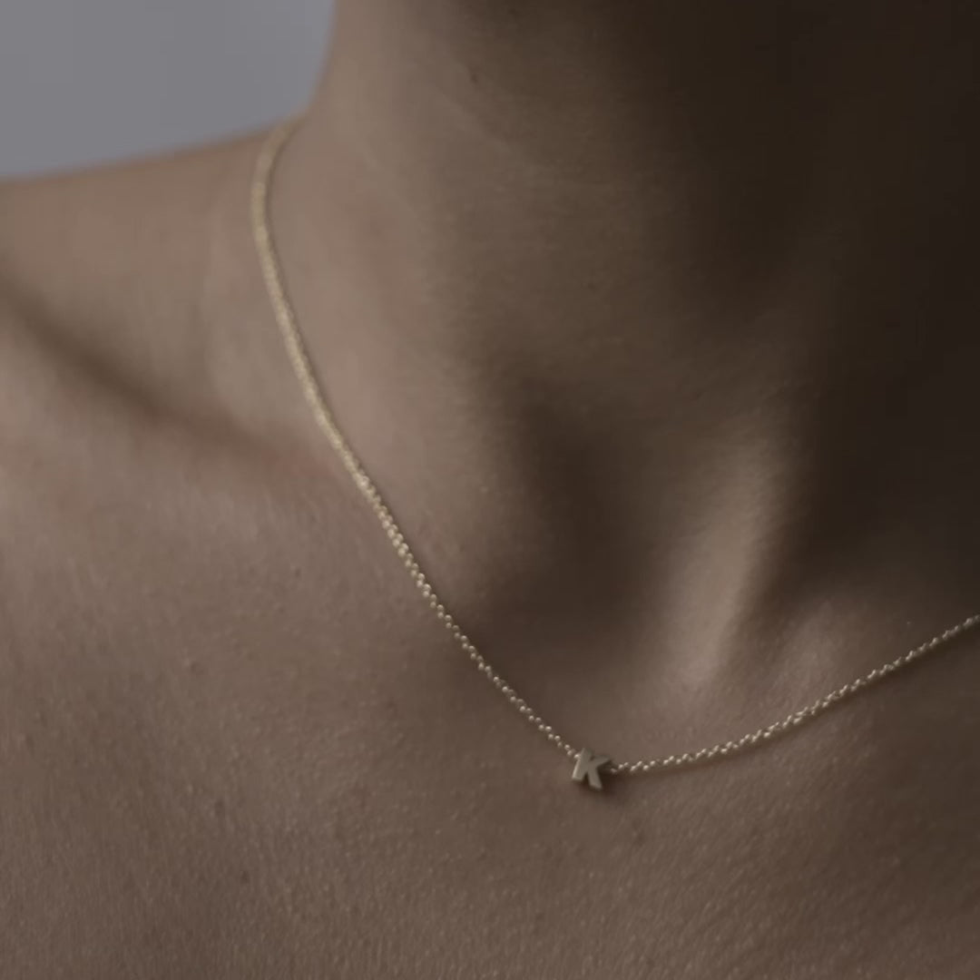 Solid gold and sterling silver jewellery: Close up video of a model wearing our signature 9ct yellow gold Tiny Letter K Charm Necklace on a 40cm cable chain
