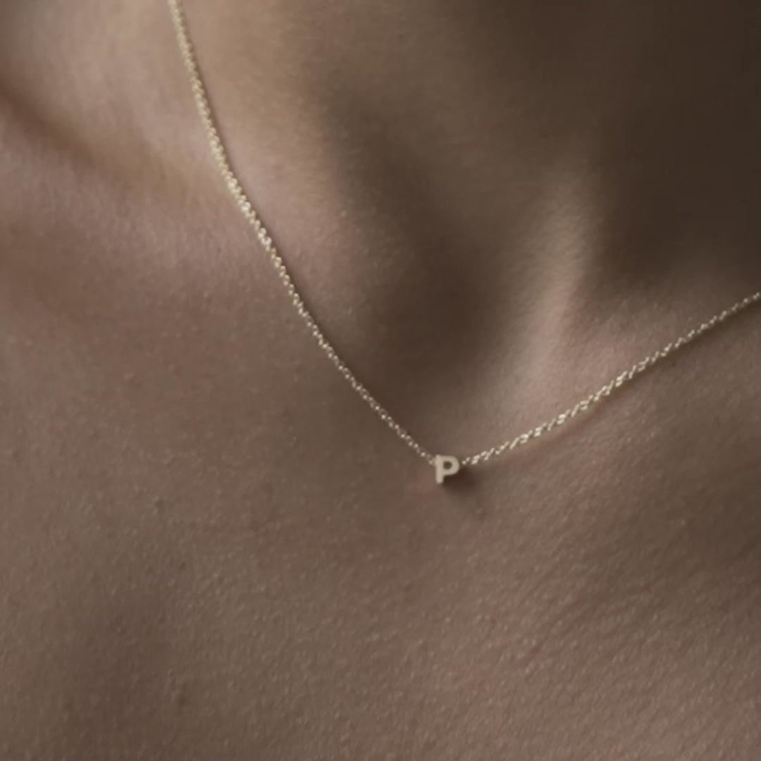 Solid gold and sterling silver jewellery: Close up video of a model wearing our signature 9ct yellow gold Tiny Letter P Charm Necklace on a 40cm cable chain