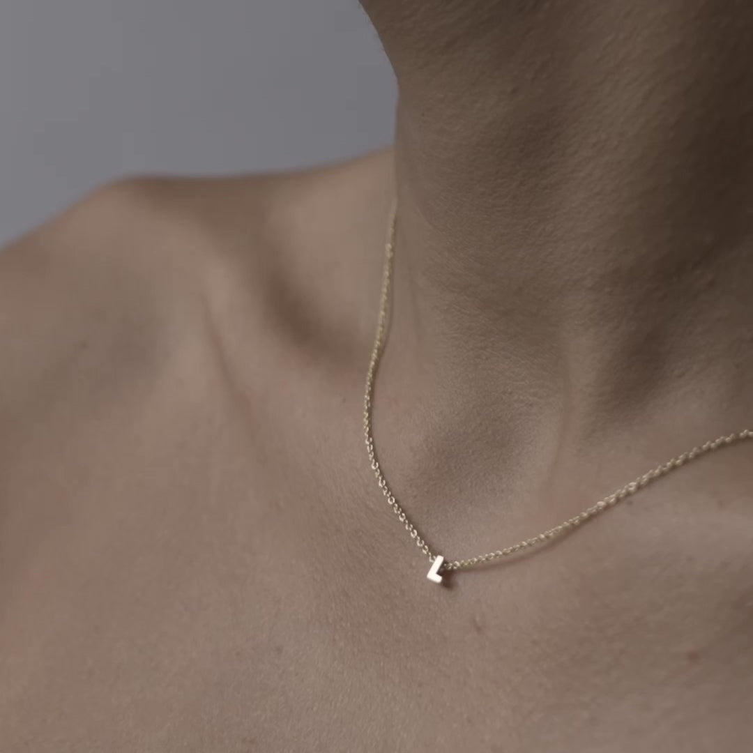 Solid gold and sterling silver jewellery: Close up video of a model wearing our signature 9ct yellow gold Tiny Letter L Charm Necklace on a 40cm cable chain