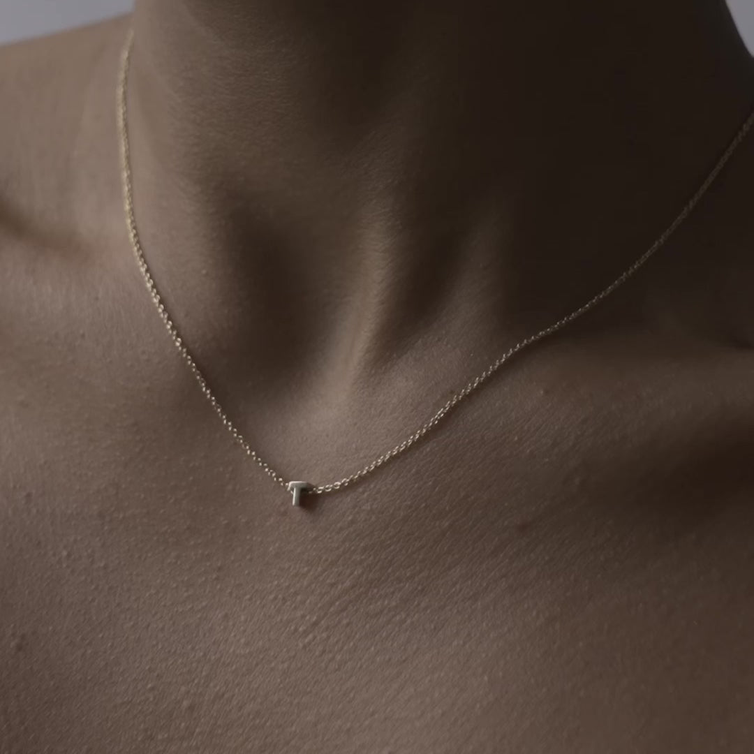 Solid gold and sterling silver jewellery: Close up video of a model wearing our signature 9ct yellow gold Tiny Letter T Charm Necklace on a 40cm cable chain