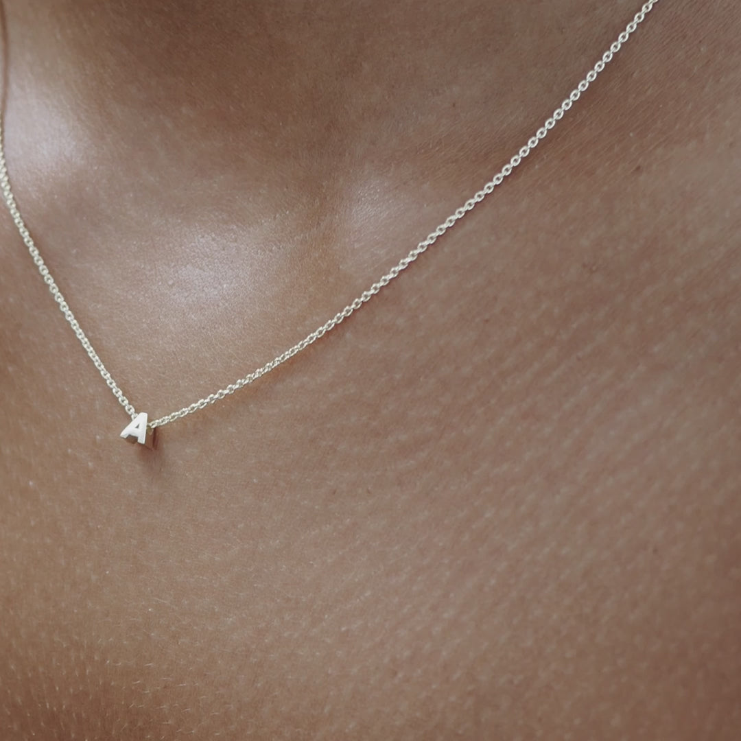 Solid gold and sterling silver jewellery: Video of a model wearing our signature sterling silver tiny letter A charm necklace on a 40cm cable chain