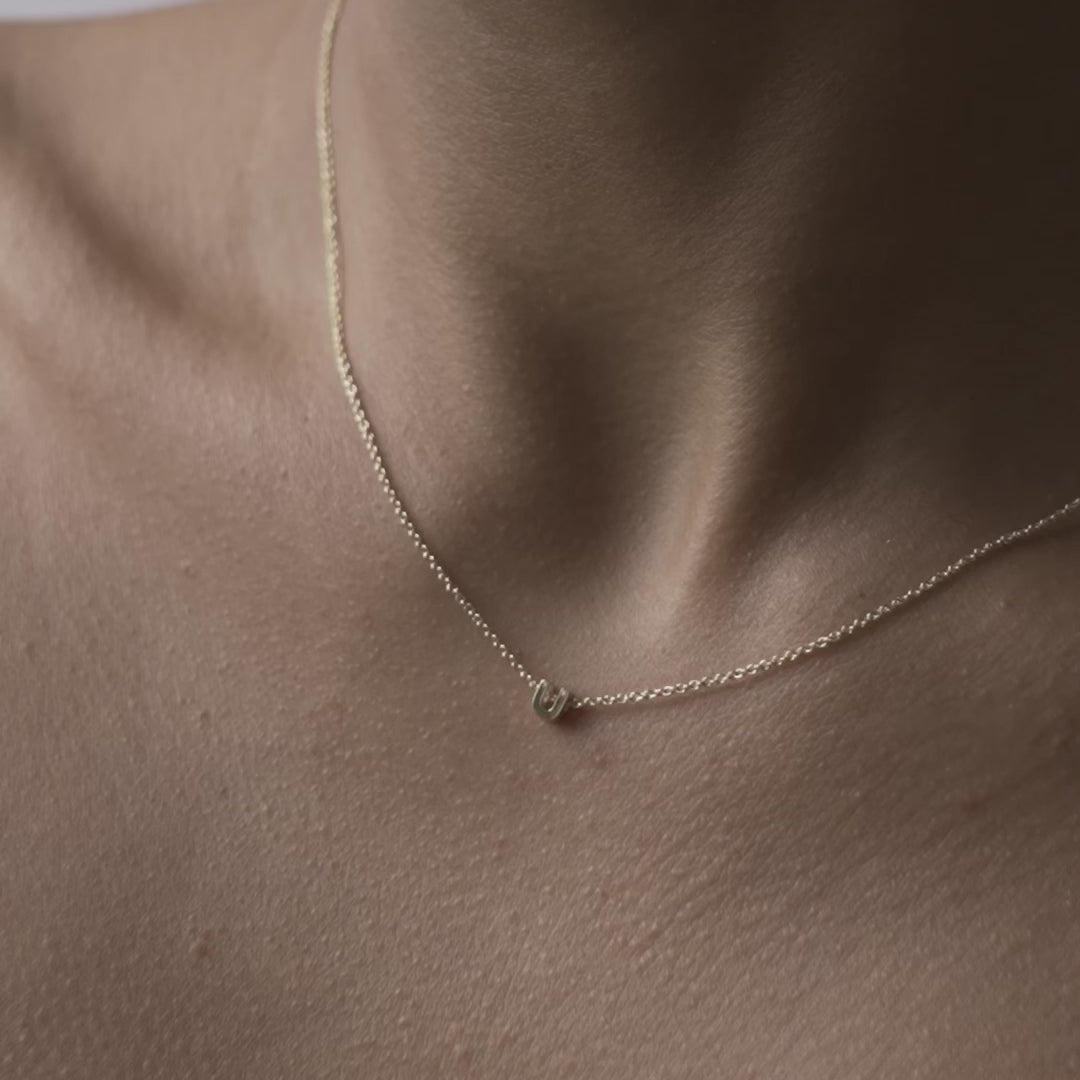 Solid gold and sterling silver jewellery: Close up video of a model wearing our signature 9ct yellow gold Tiny Letter U Charm Necklace on a 40cm cable chain
